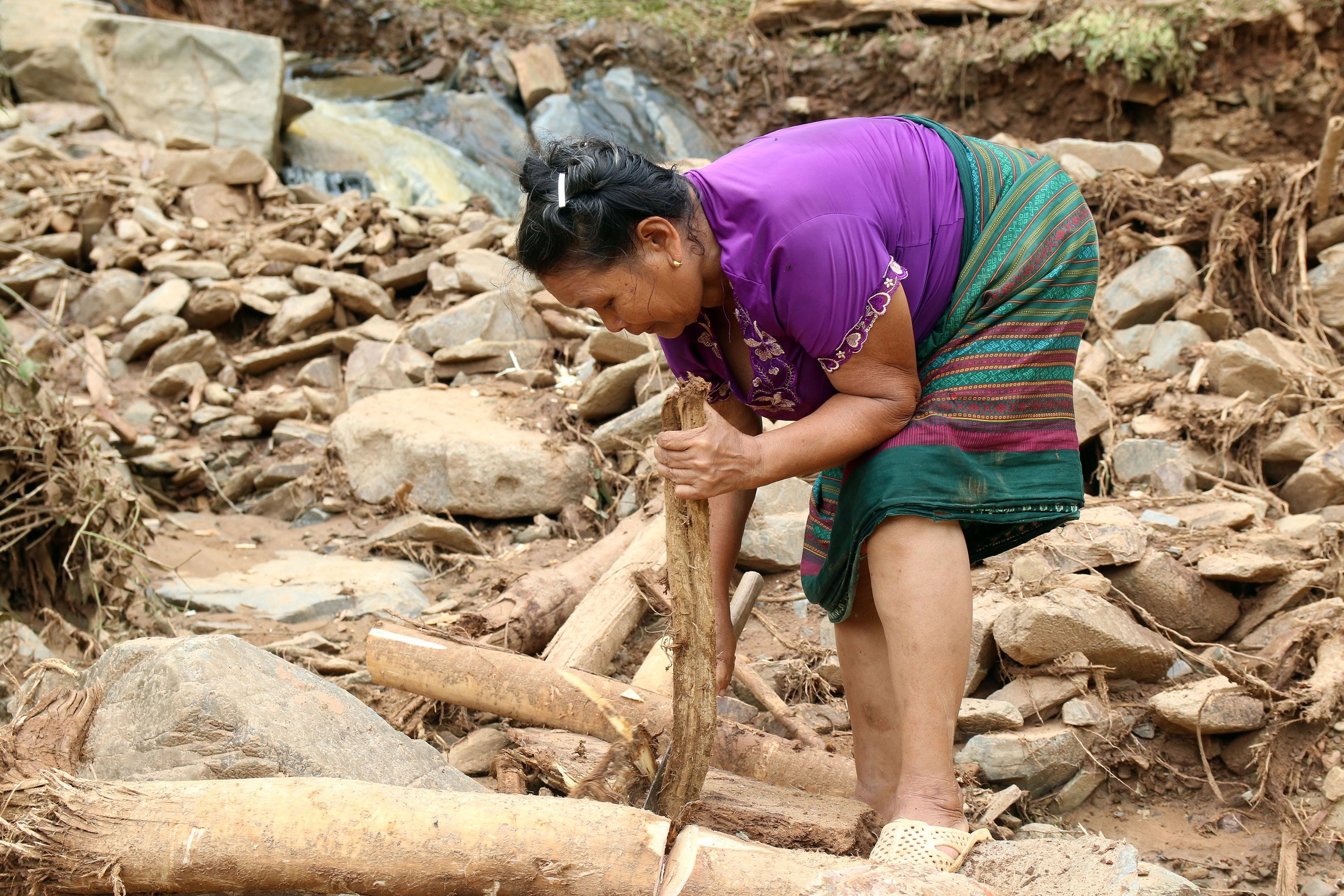 Một cụ già nhặt nhạnh những thanh củi trôi về trong sạt lở. Ảnh: Tràng Tràng - Minh Khuê