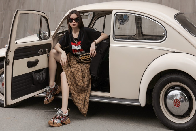 Với mẫu giày của Gucci, cô chọn áo thun in họa tiết chữ size lớn, đi cùng chân váy midi có họa tiết bắt màu. Mốt túi đeo ngang hông cũng được cô áp dụng cho ngoại hình.