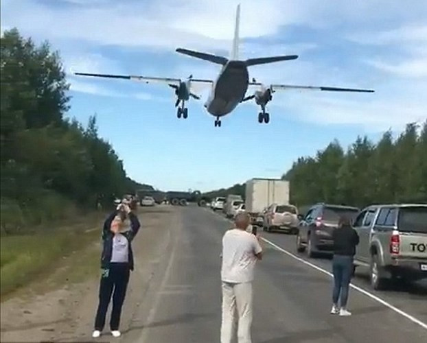 Người đi đường thích thú quay phim cảnh phi cơ quân sự bay sát ngay trên đầu họ.