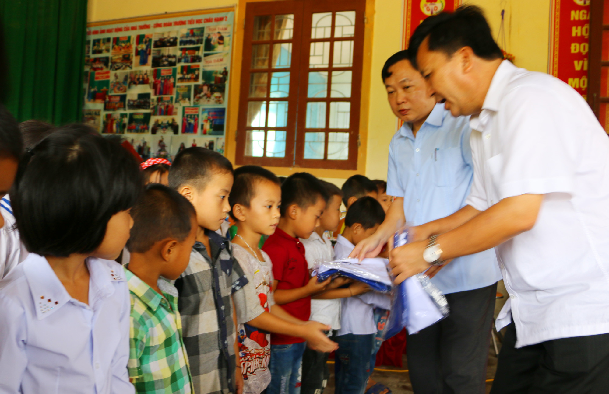 Đại diện Điện lực Nghệ An và lãnh đạo huyện Quỳ Châu cùng trao quà cho các học sinh nghèo lớp 1. Ảnh: Nguyễn Hải
