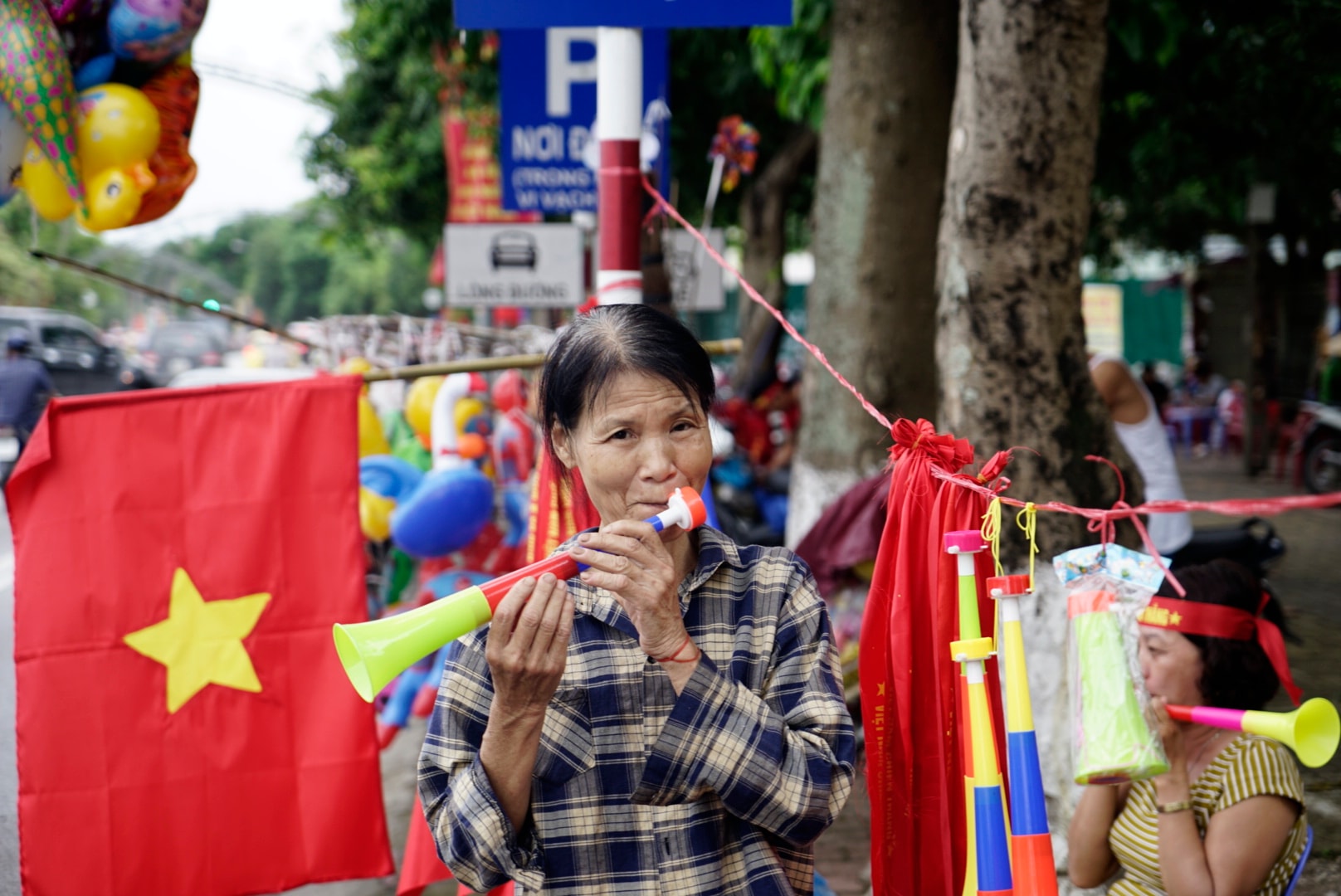 Một bà lão phấn khích khi trước trận đấu, bà bán được rất nhiều kè, áo, băng rôn. Ảnh: Lê Thắng