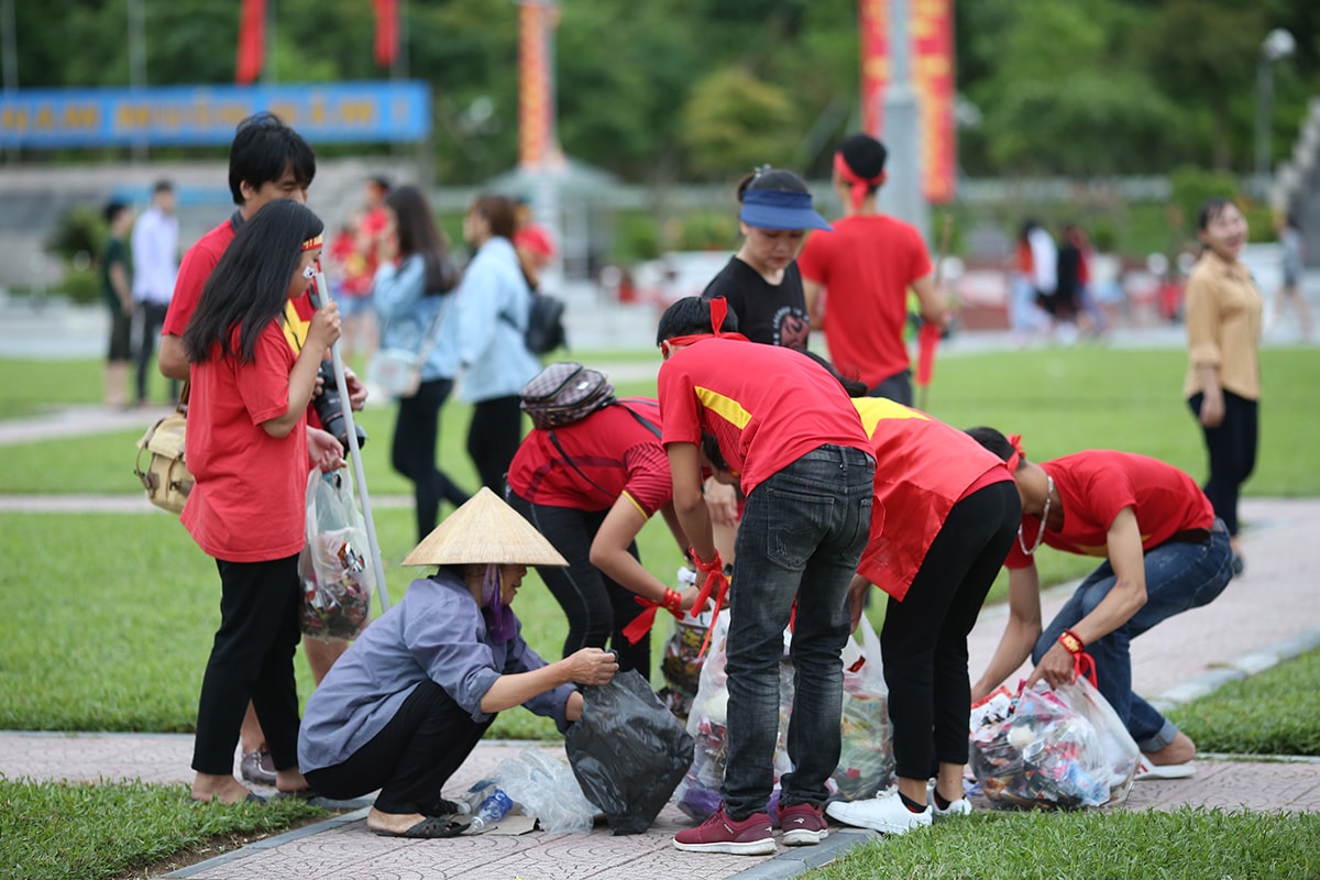 Kết thúc trận đấu, các bạn trẻ Nghệ An giúp đỡ các chị nhân viên môi trường thu dọn đống phế liệu và rác thải. Ảnh: Hoài Hoan