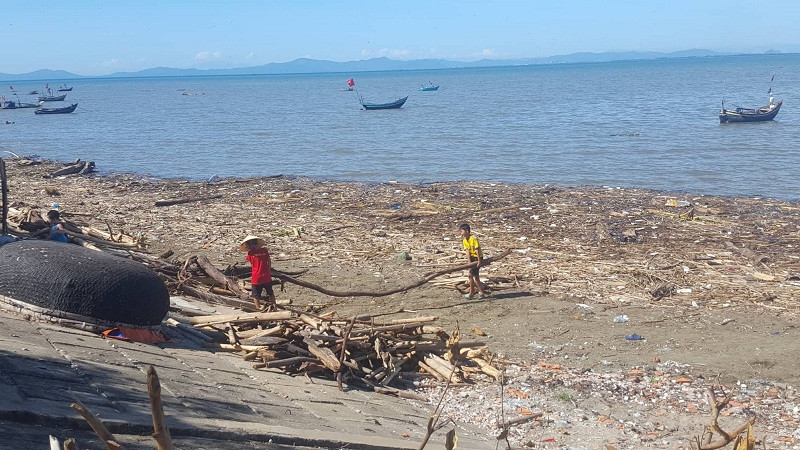 Người dân tranh thủ vớt củi từ biển rác. Ảnh Thạch Quỳnh
