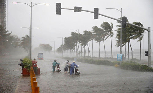 Người đi xe máy chống chọi lại mưa lớn và gió mạnh khi siêu bão Mangkhut đổ vào miền đông bắc Philippines rạng sáng ngày 15/9 tại thủ đô Manila, Philippines. Ảnh: AFP.