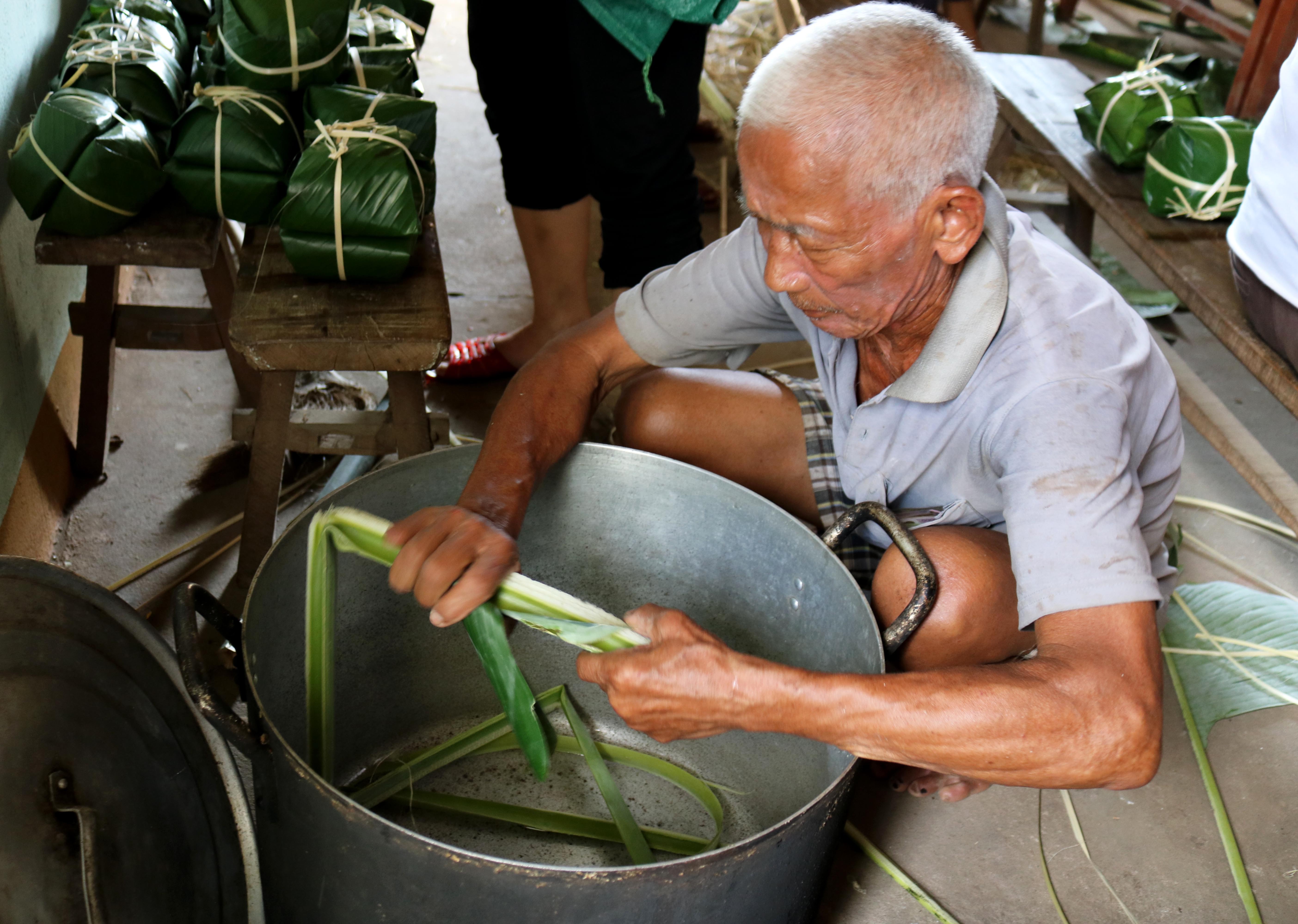 Một cụ ông chuẩn bị nồi trước khi nấu bánh. Ảnh: Huy Thư