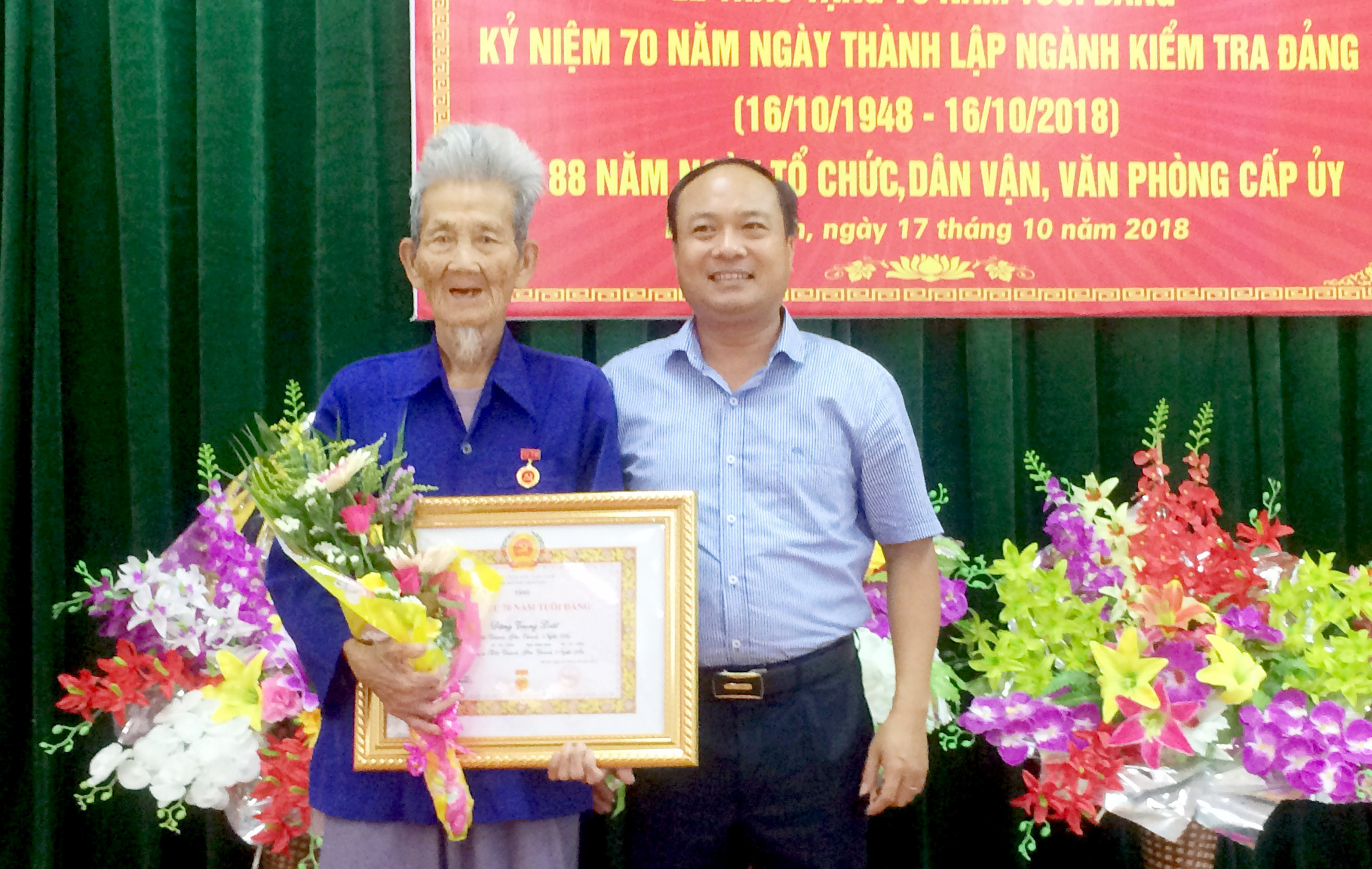 Đồng chí Nguyễn Viết Hưng - Phó Bí thư Thường trực Huyện ủy Yên Thành trao Huy hiệu 70 năm tuổi Đảng cho đảng viên Đặng Trọng Loát.