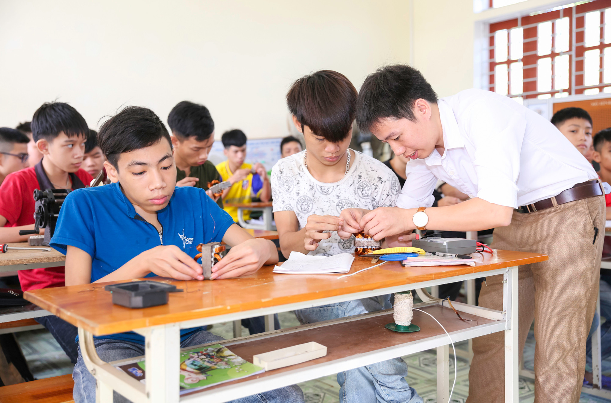 Thầy Thái Khắc Minh hướng dẫn học sinh khiếm thính thực hành về điện.  Ảnh:  Đức Anh