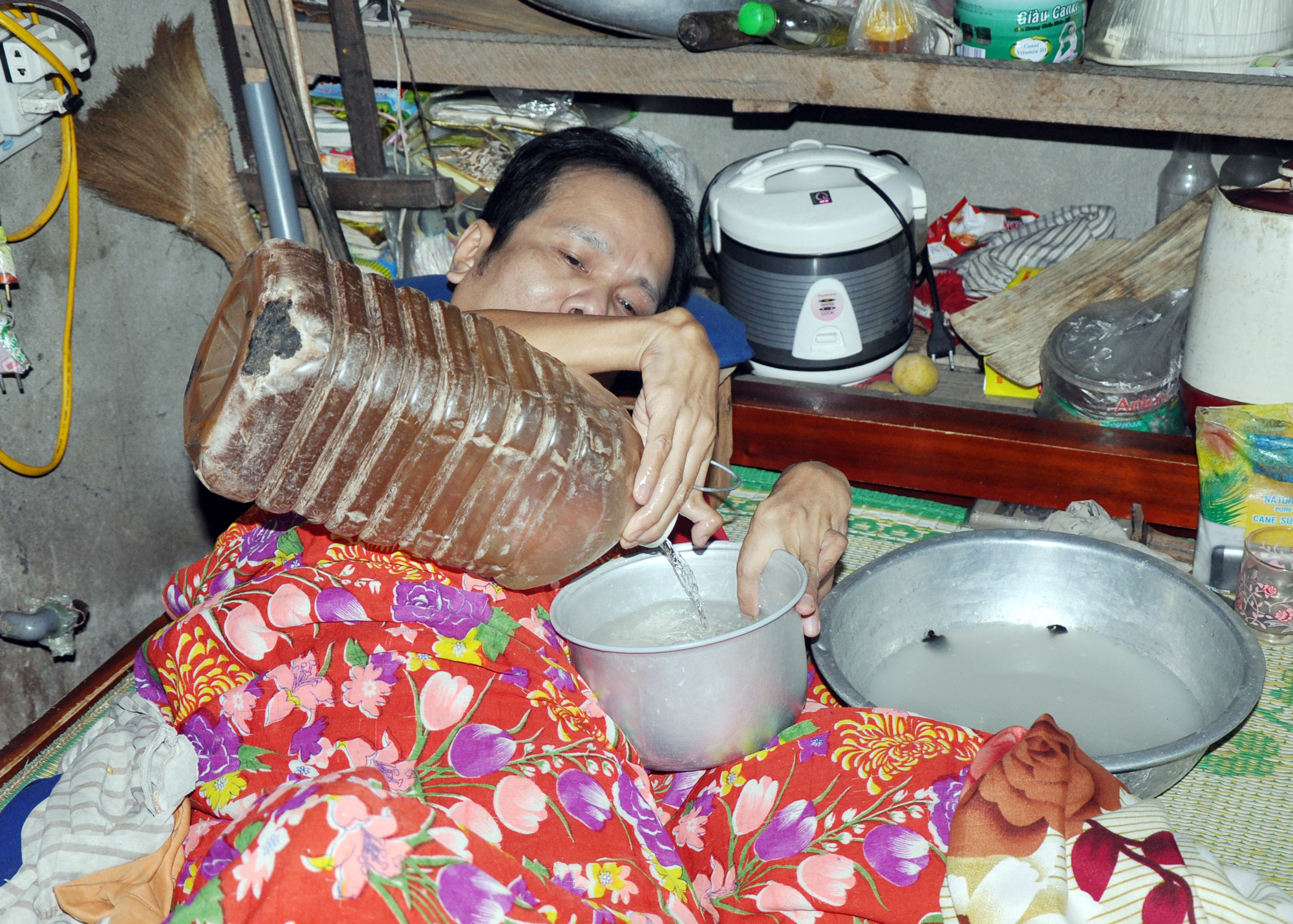 Những khi ở nhà một mình, ông Nguyễn Hải Yến có thể hứng nước để vò gạo và nấu cơm bằng nồi điện.  Ảnh: Tường Anh