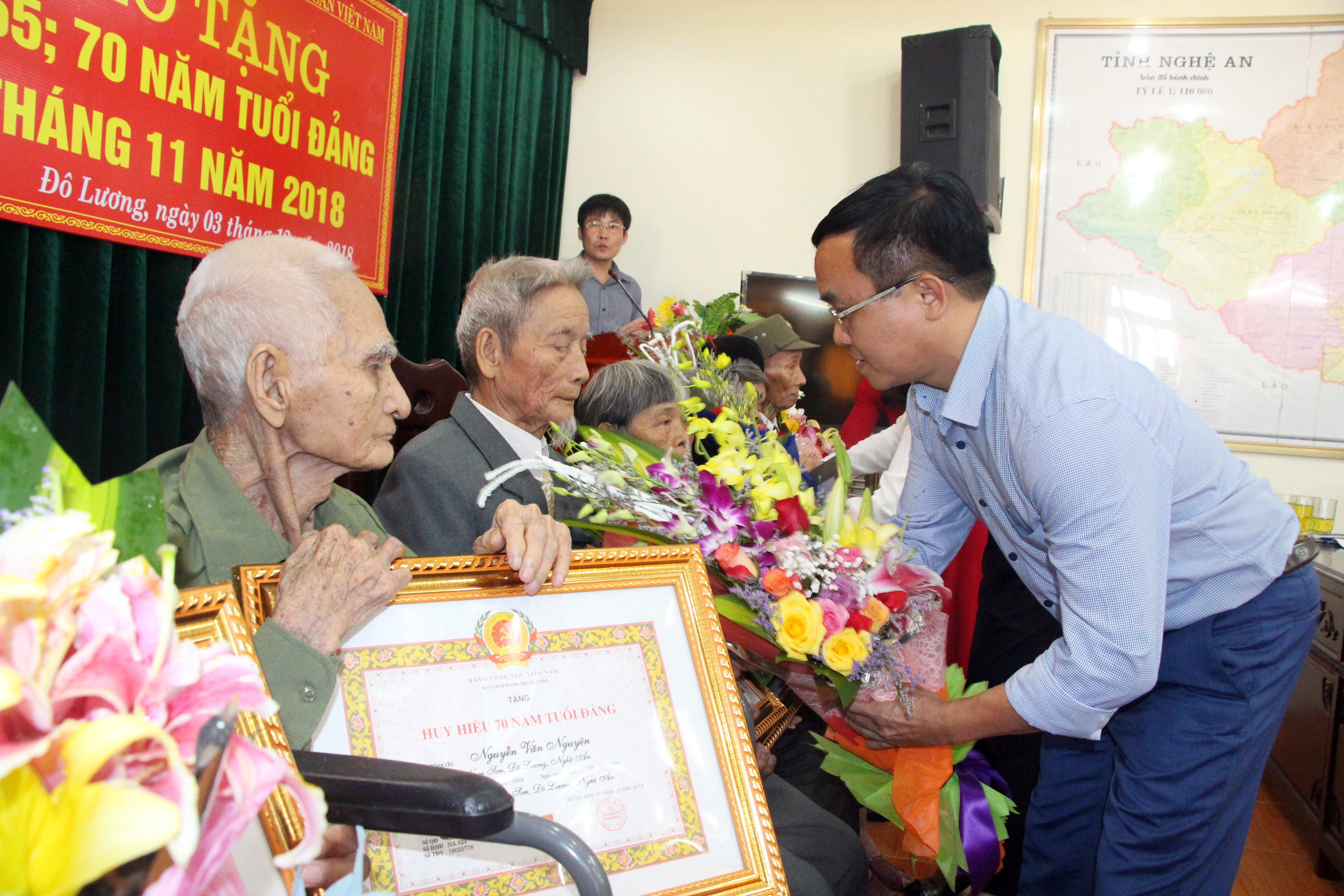 Đồng chí Ngọc Kim Nam - Bí thư Huyện ủy Đô Lương tặng hoa chúc mừng các đảng viên lão thành. Ảnh: Đào Tuấn