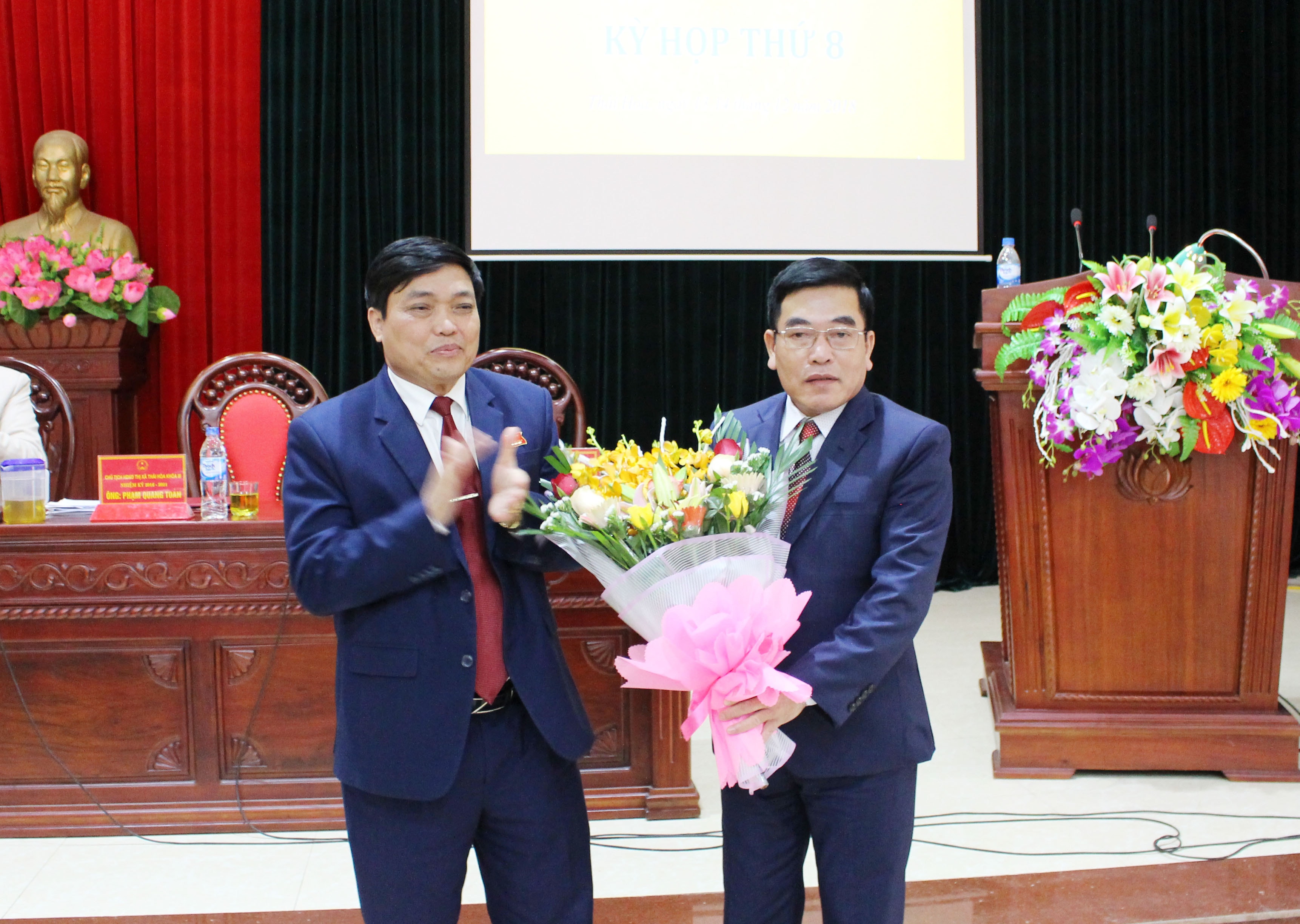 Ông Phạm Quang Toản - Phó Bí thư Thường trực Thị ủy, Chủ tịch HĐND thị xã tặng hoa chúc mừng Phó Chủ tịch UBND thị xã Đinh Thế Vinh. Ảnh: Hoàng Thủy