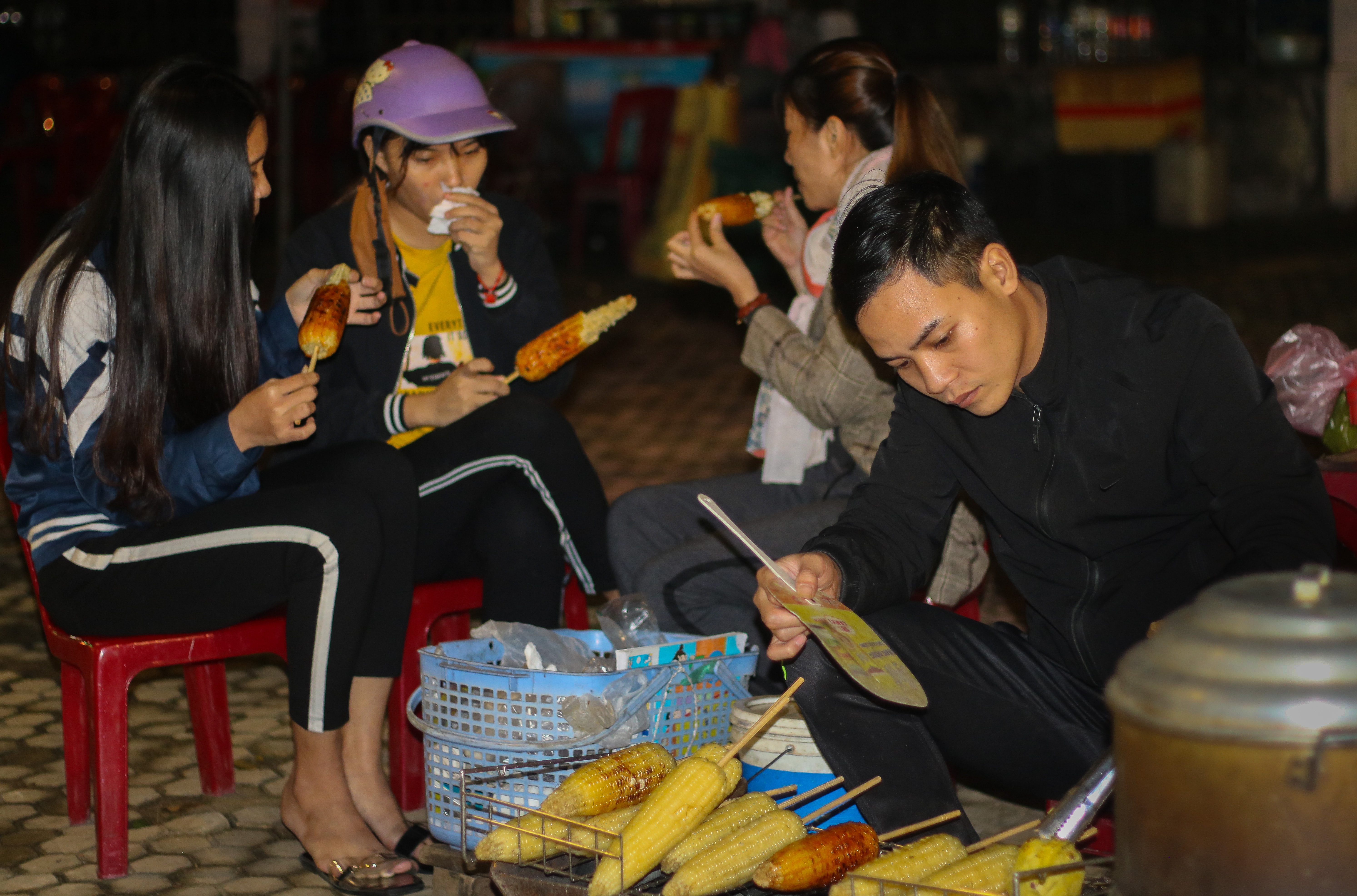 Ngồi nhìn anh chủ nướng ngô, vui vẻ “bàn chuyện thiên hạ” cùng chúng bạn và không khỏi xuýt xoa với bắp ngô, khoai nướng thơm lừng, dịu ngọt khi thưởng thức. Ảnh: Diệp Phương