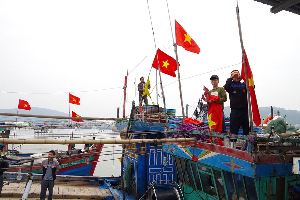 Ngư dân treo cờ Tổ quốc mới được tặng lên tàu thuyền. Ảnh: Hoàng Anh