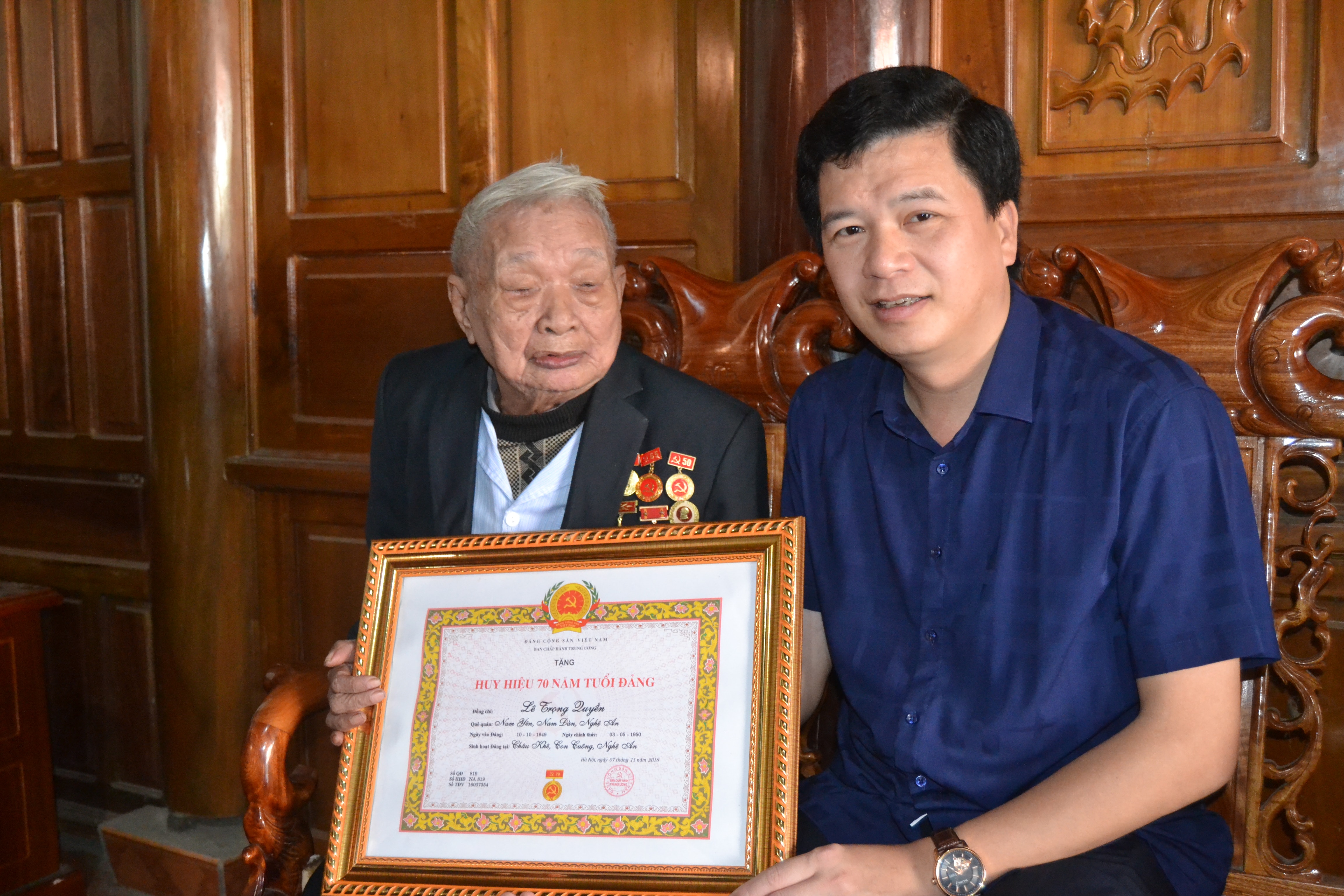 Đồng chí Nguyễn Đình Hùng-Bí thư Huyện ủy trao huy hiệu 70 năm tuổi Đảng cho đồng chí Lê Trọng Quyền (Khe Choăng xã Châu Khê)
