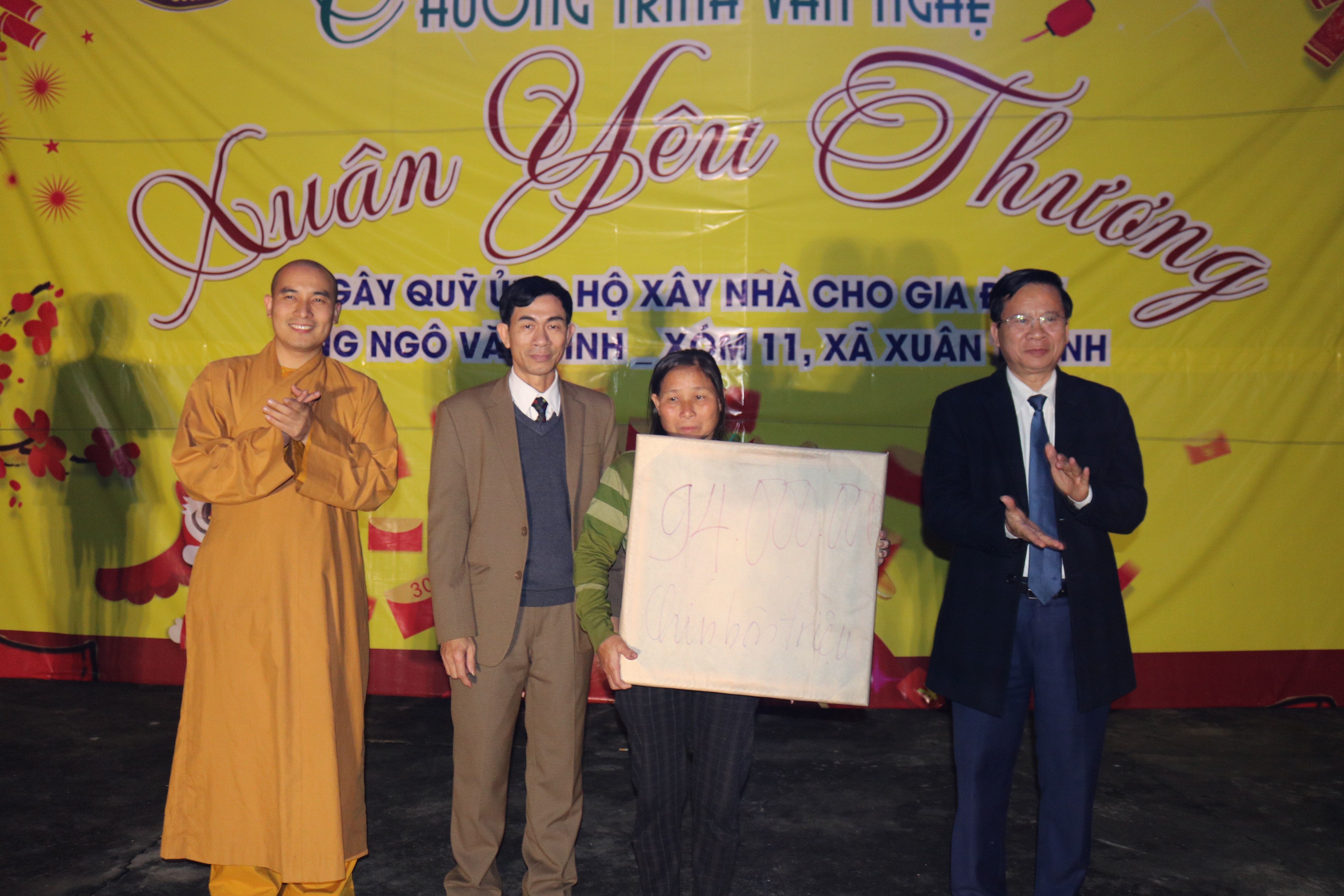 Đại đức Thích Tuệ Minh trụ trì chùa ChíLinh và ông Phan Văn Tuyên - Chủ tịch UBND huyện YênThành trao quà cho gia đình ông Bình  tại sân khấu. Ảnh: Huy Thư