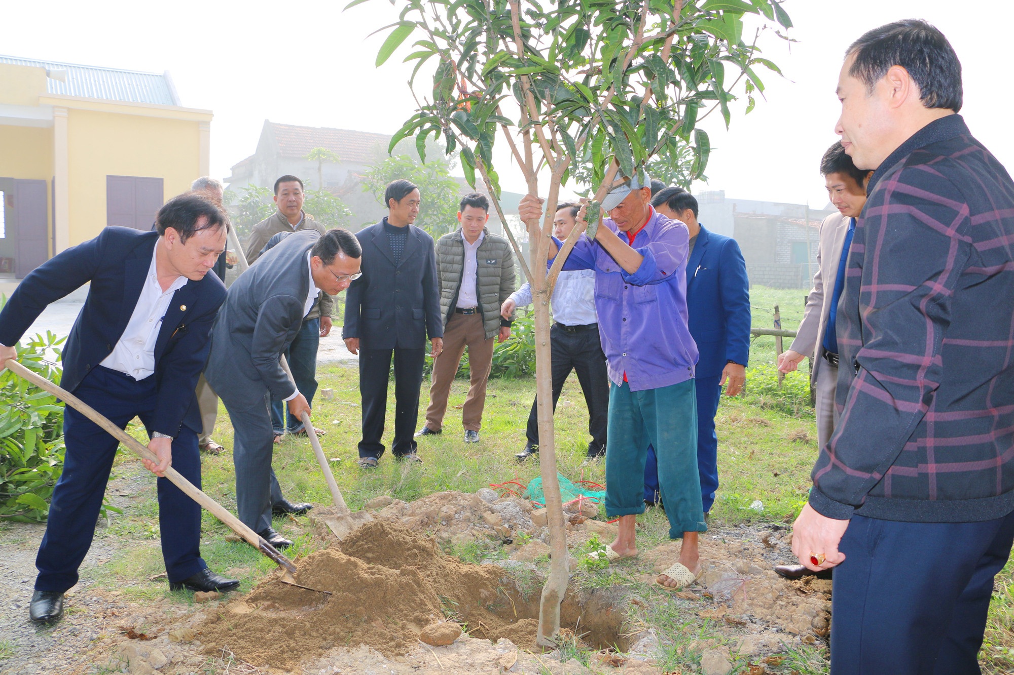 Đồng chí Hồ Phúc Hợp và lãnh đạo huyện Nghi Lộc trồng cây lưu niệm tại Nhà văn hóa xóm 2, xã Nghi Thuận. Đây là món qua do cán bộ, công chức Ban Tổ chức quyên góp, ủng hộ. Ảnh: Nguyễn Hải