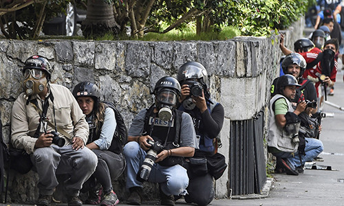 Các nhà báo ẩn nấp khi cuộc biểu tình bùng phát thành bạo động tại thủ đô Caracas, tháng 6/2017. Ảnh: JB.