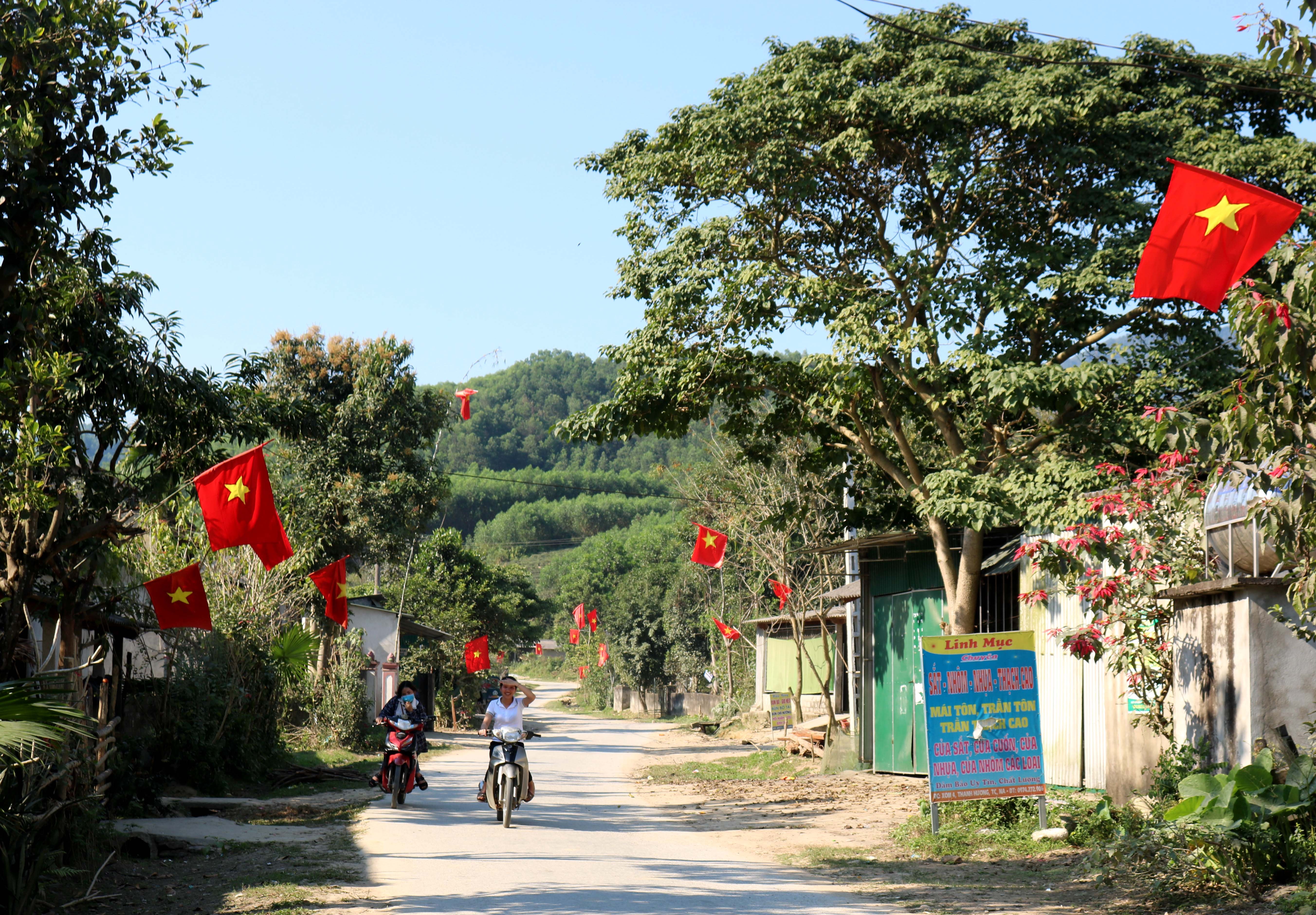 Trong nắng Xuân vàng, đường về các bản tái định cư rợp sắc cờ Tổ Quốc.