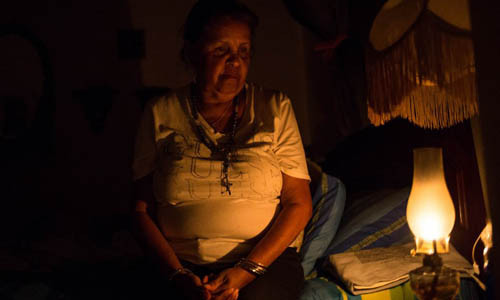 Một phụ nữ Venezuela dùng đèn dầu để thắp sáng ngôi nhà tại Caracas hôm 9/3. Ảnh: AFP.