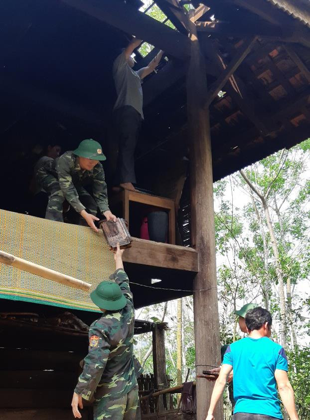 Lực lượng đồn BP và địa phương giúp nhân dân thu dọn vệ sinh, lợp lại nhà bị tốc mái. Ảnh: Hải Thượng