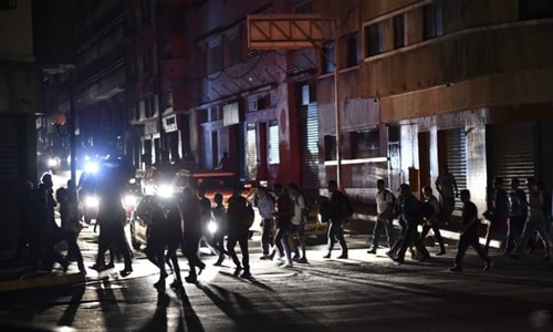 Người dân băng qua khu phố mất điện ở thủ đô Caracas hôm 8/3. Ảnh: AFP.