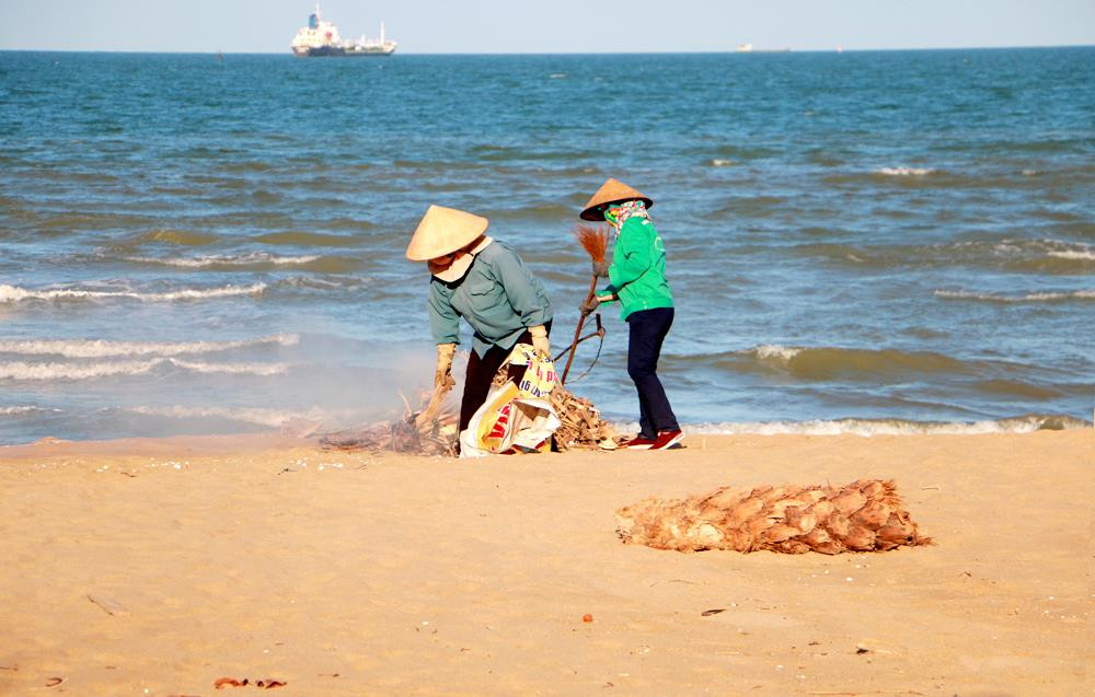 Công nhân Công ty CP Môi trường đô thị và Dịch vụ du lịch Cửa Lò thu gom rác thải trên bãi biển. Ảnh: Lâm Tùng