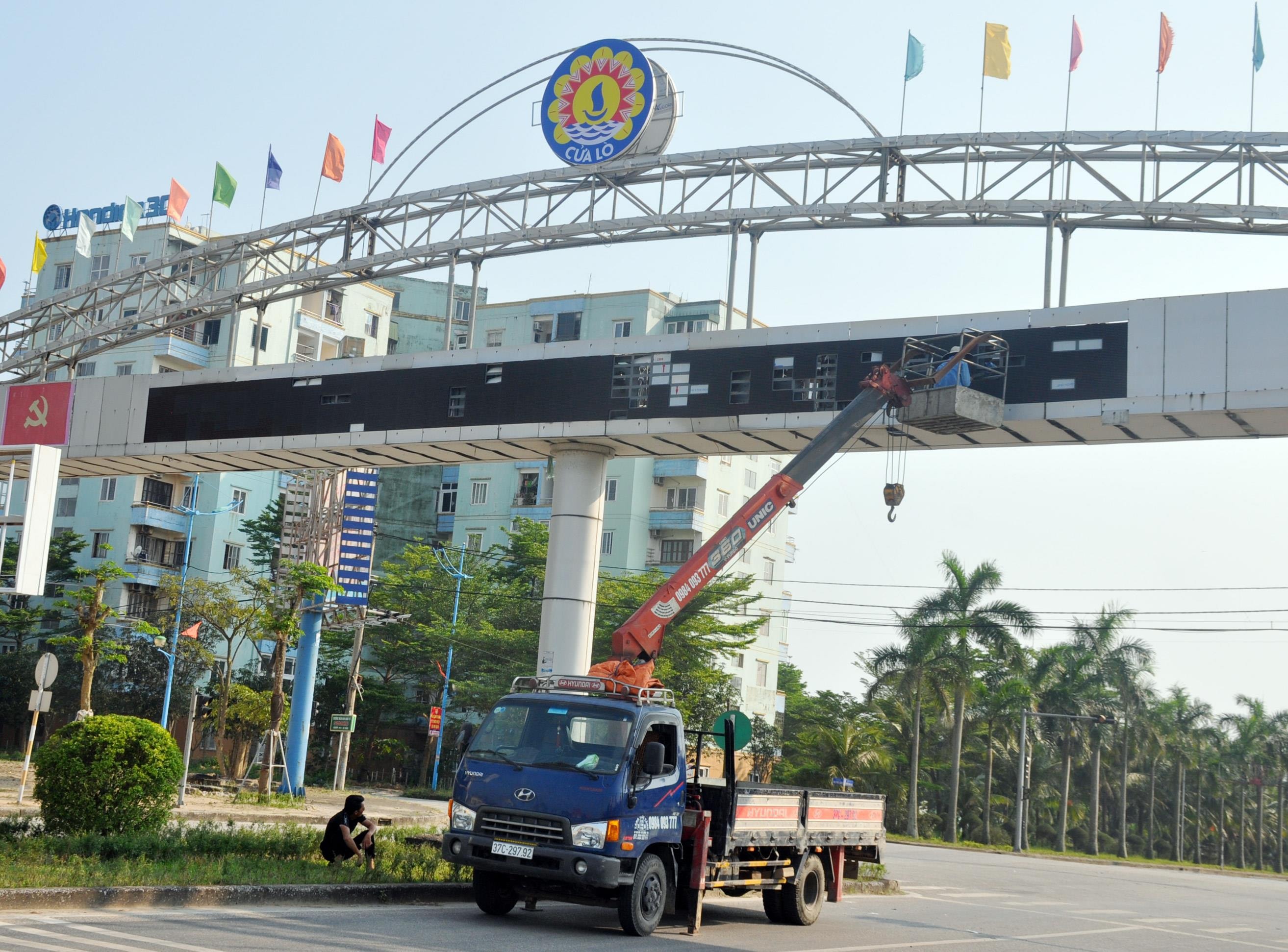 Công nhân lắp đặt trang trí cổng chào lớn trên đường Nguyễn Sinh Cung. Ảnh: Việt Phương