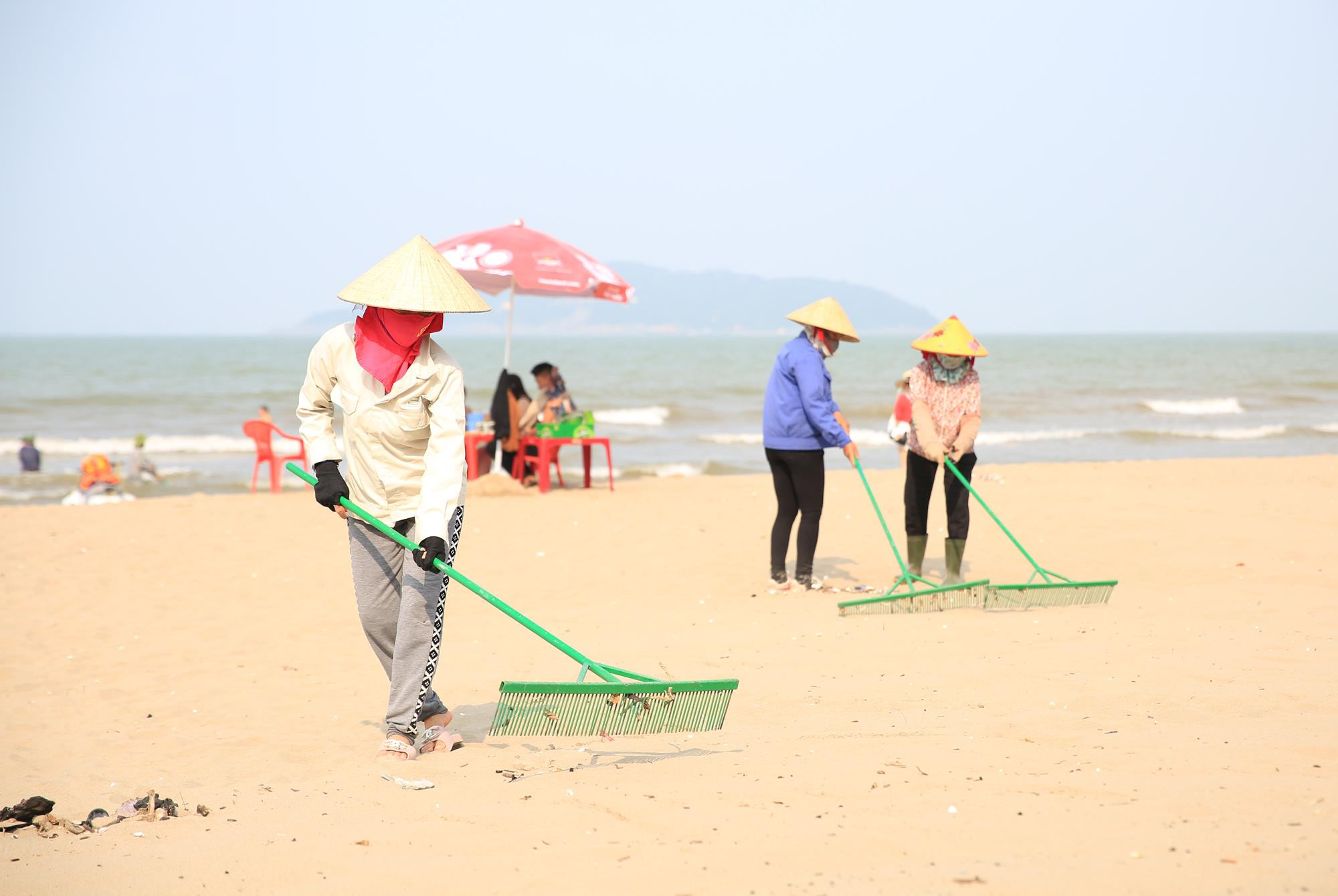 Sợ vỏ sò, ốc làm đau cho đôi chân trần của du khách, người dân thị xã biển hiếu khách ra sức làm sạch cát biển thêm mịn màng. Ảnh: Hồ Phương