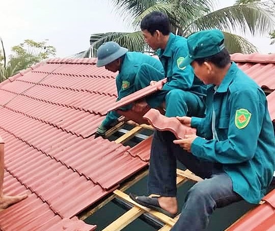 Lực lượng dân quân của huyện đang giúp nhân dân xã Tiên Kỳ lợp lại nhà sau cơn lốc xoáy