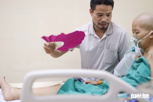 Anh Đỗ Văn Hùng, chồng của chị Nguyễn Thị Liên, chăm sóc cho vợ tại Bệnh viện K chiều 23-5 - Ảnh: NGUYỄN KHÁNH