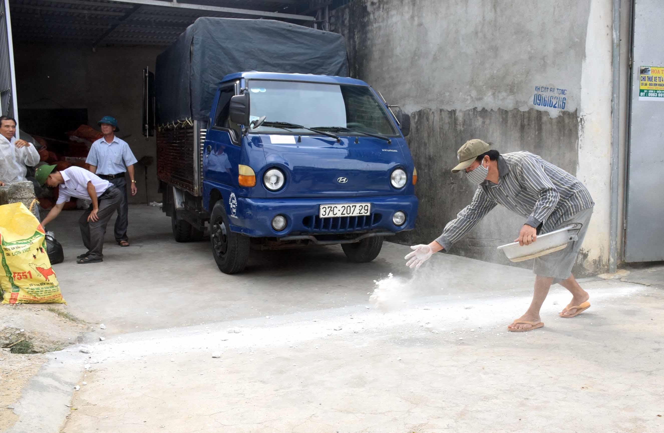 Ông Nguyễn Hữu Sáng rắc vôi bột trước cổng nhà. Ảnh: Xuân Hoàng 