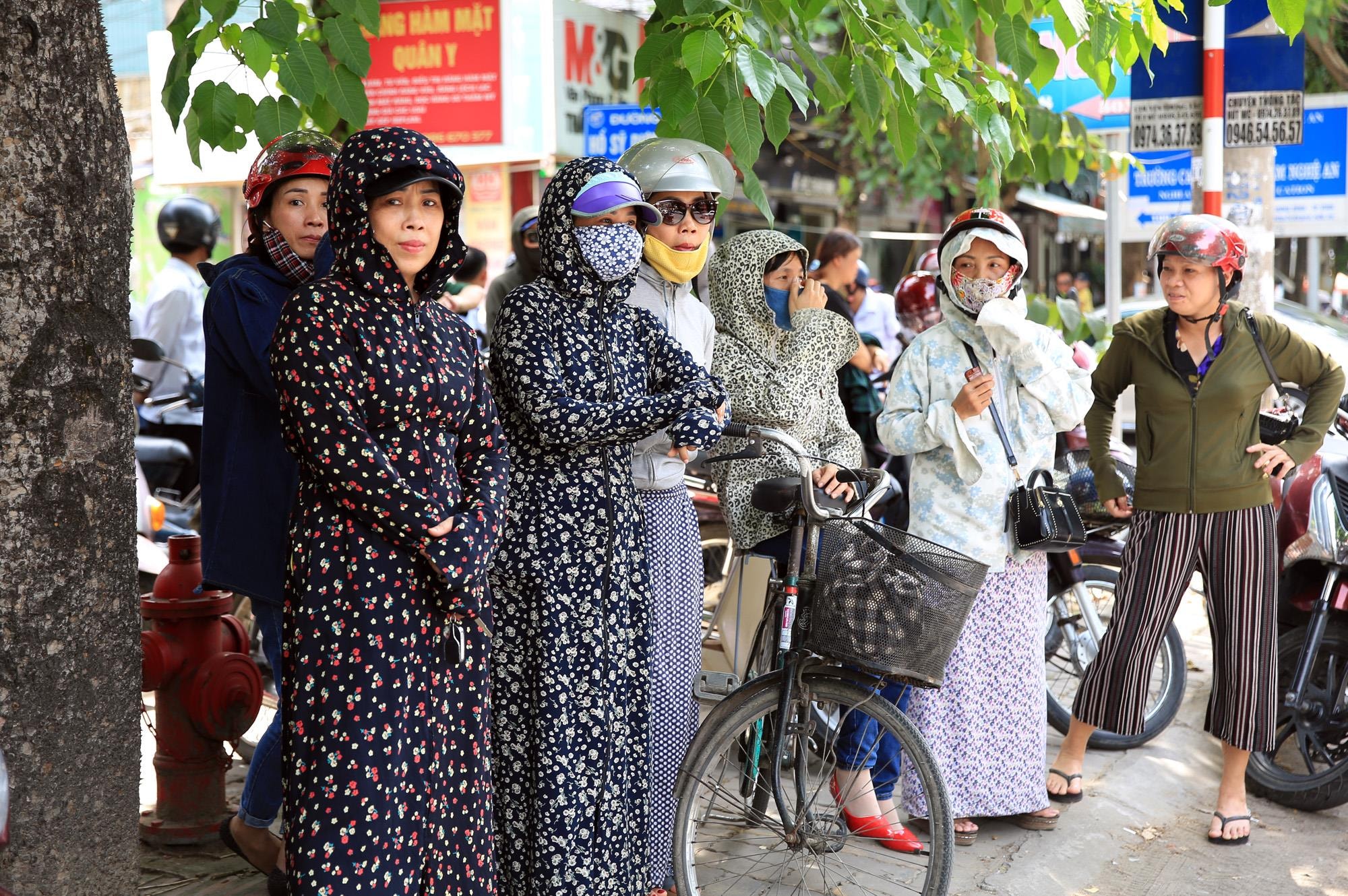 Nhiều bậc phụ huynh phải bịt kín để chống lại nắng nóng đổ lửa của TP Vinh trong ngày đầu diễn ra thi. 
