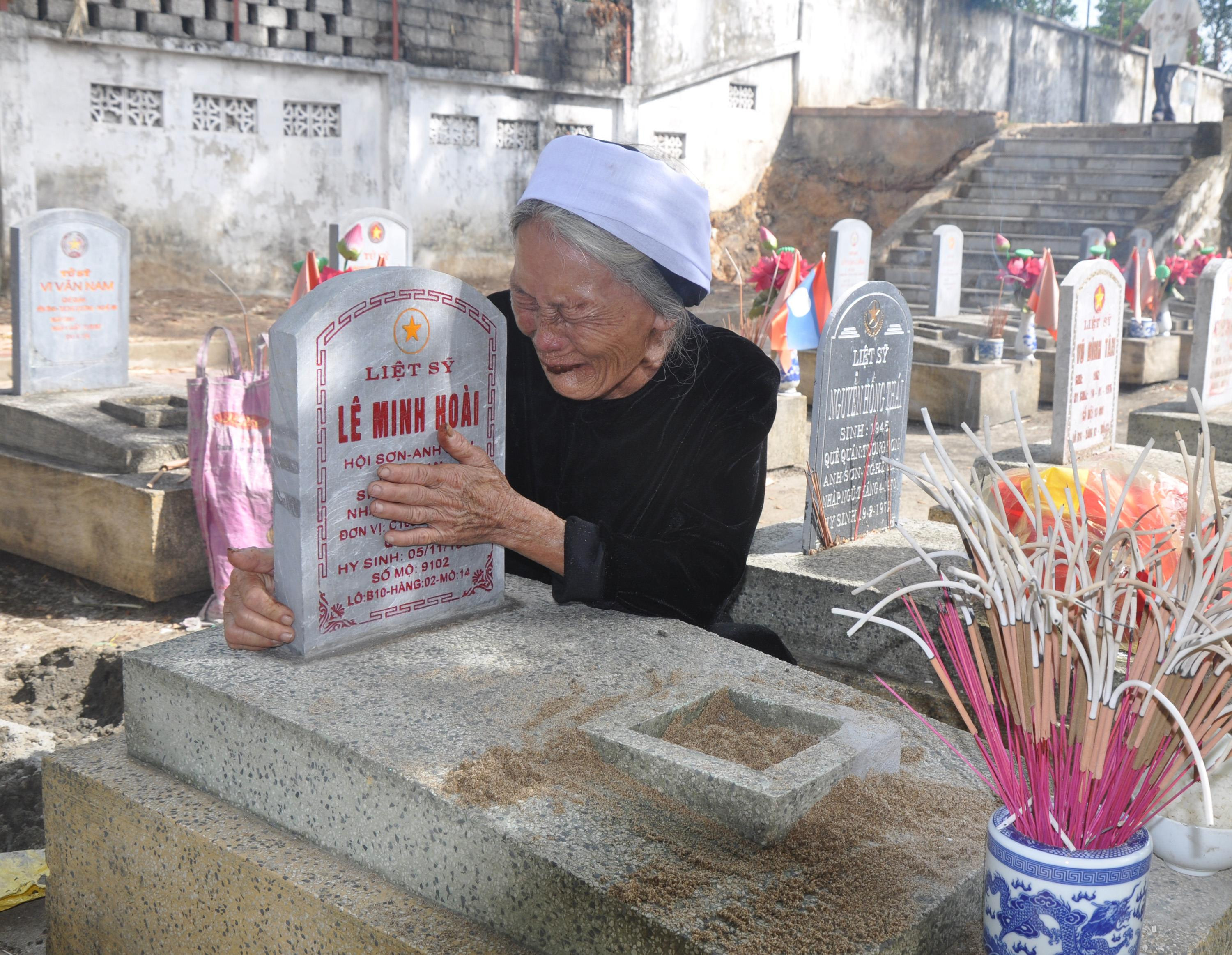 Bà Nguyễn Thị Tứ (vợ liệt sỹ Lê Minh Hoài) bên mộ chồng. Ảnh: Công Kiên