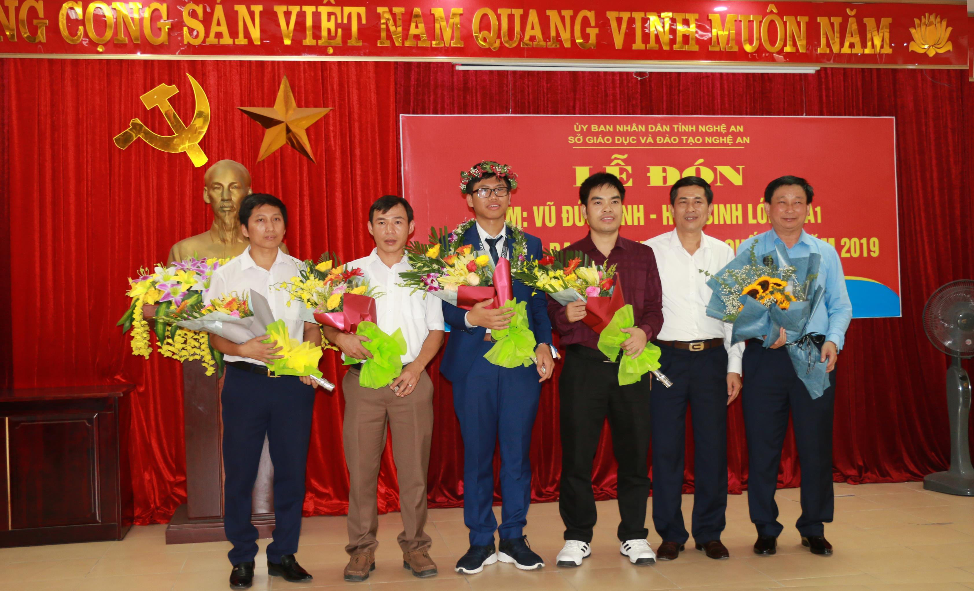 Giám đốc Sở Giáo dục và Đào tạo Thái Văn Thành tặng hoa cho em Vũ Đức Vinh và các thầy giáo trong tổ bồi dưỡng. Ảnh: Mỹ Hà