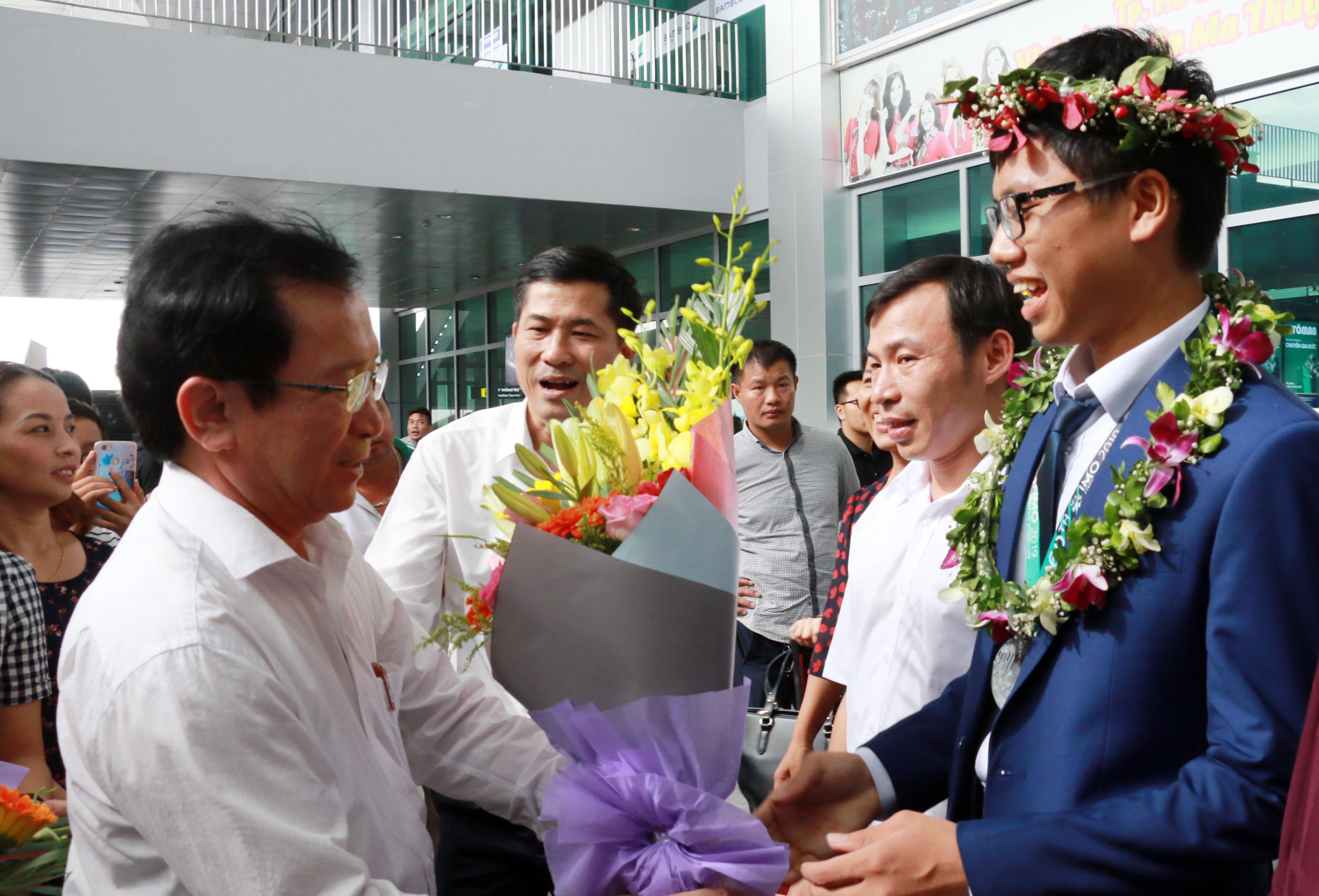 Phó Chủ tịch UBND tỉnh  Đinh Viết Hồng tặng hoa cho em Vũ Đức Vinh tại lễ đón ở sân bay. Ảnh: Mỹ Hà