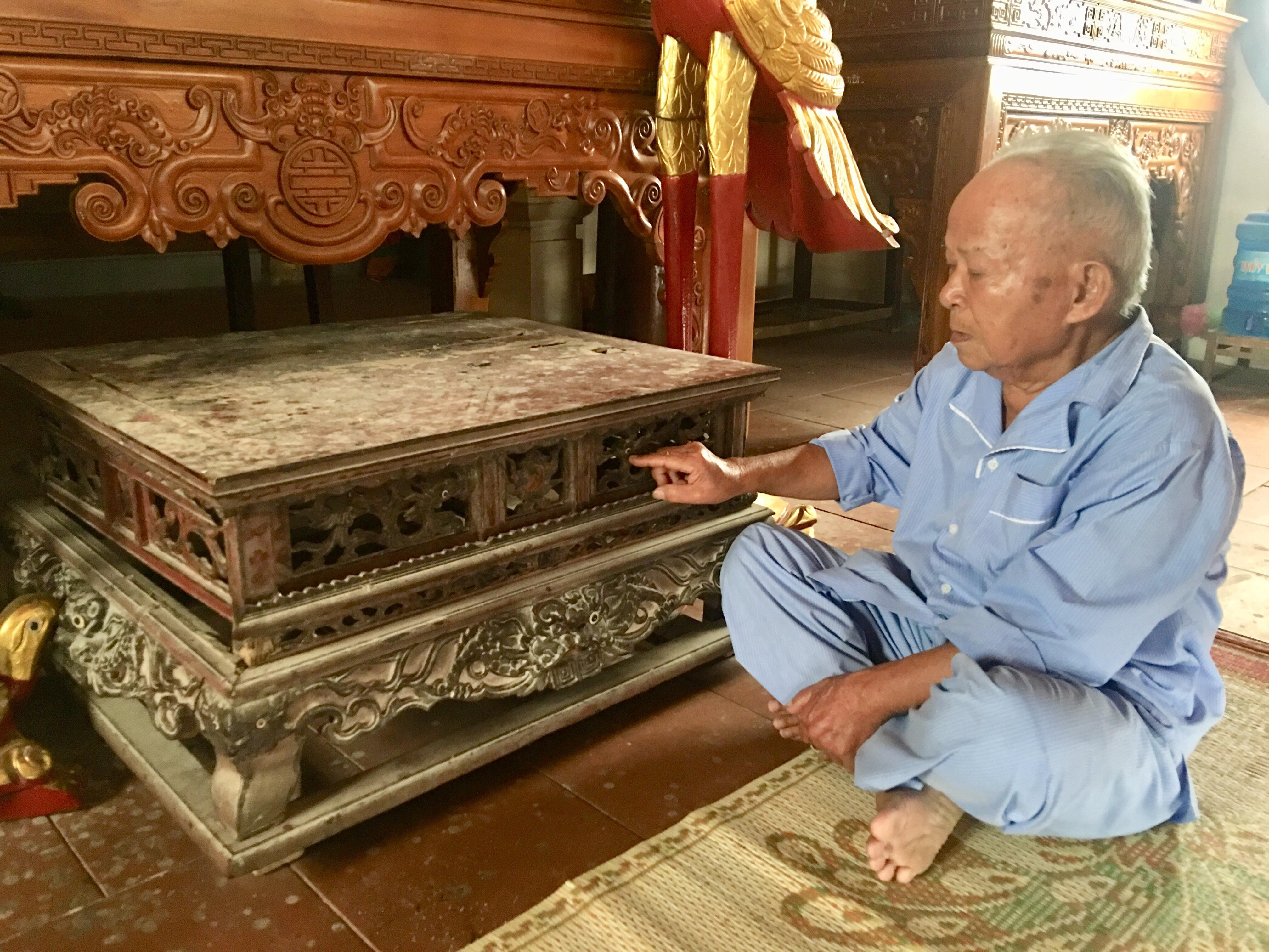 Ông Trần Văn Thanh, người trông coi đền bên chiếc bàn cổ dùng để đặt lễ tế