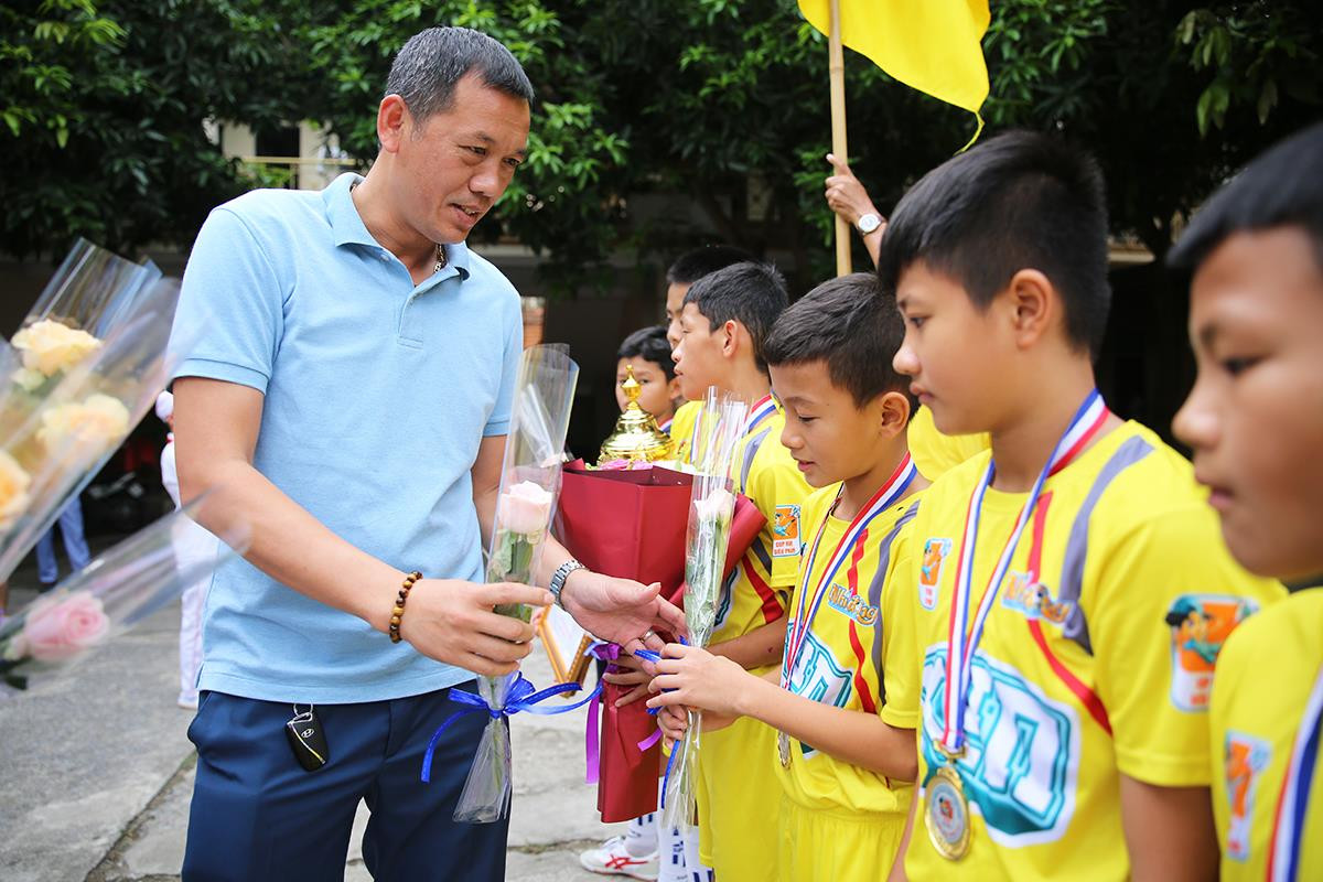 HLV trưởng đội 1 Nguyễn Đức Thắng tặng hoa cho các cầu thủ nhí vừa mang vinh quang trở về. Ảnh: Đức Anh