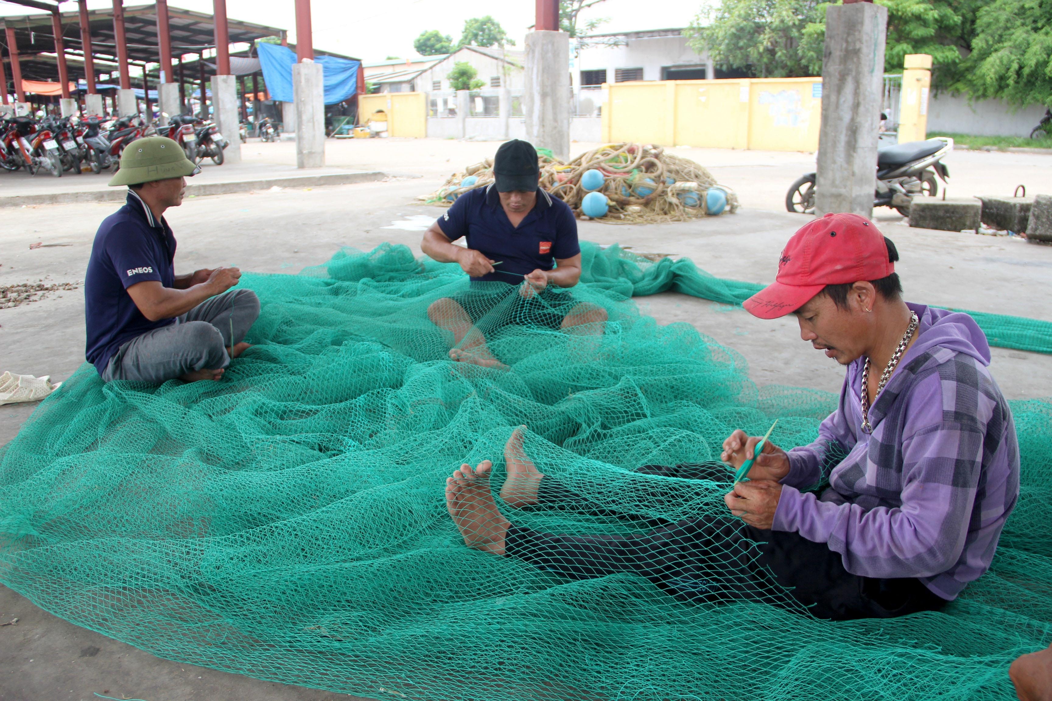 Nhiều ngư dân tranh thủ những ngày nghỉ biển, vá lưới, sửa chữa ngư cụ. Ảnh: Quang An