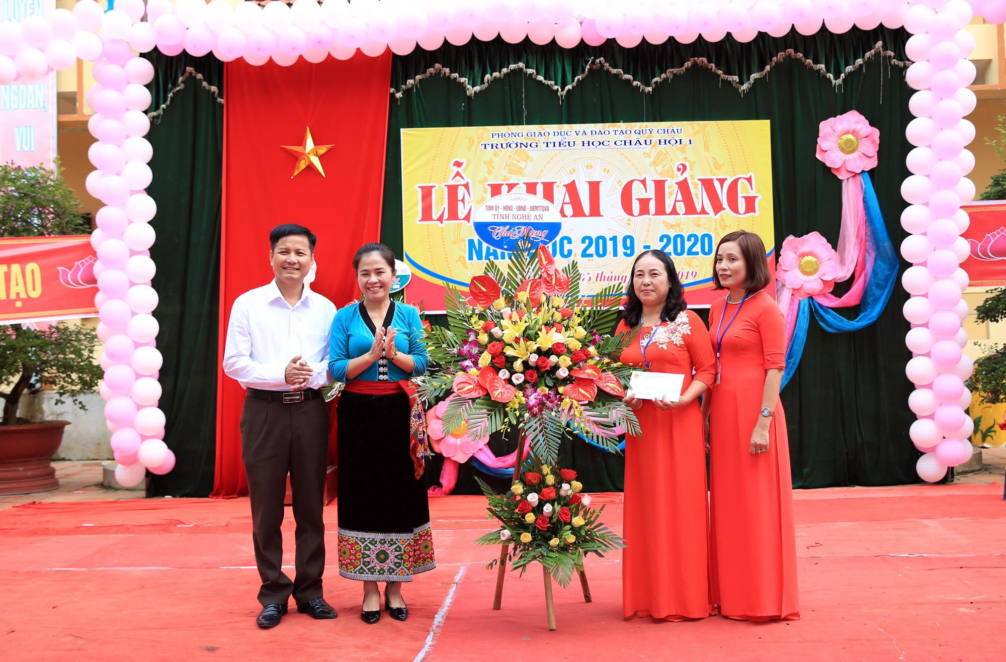 Đại diện lãnh đạo tỉnh, Sở Giáo dục và Đào tạo trao hoa và quà của tỉnh cho lãnh đạo nhà trường. Ảnh: Hồ Phương