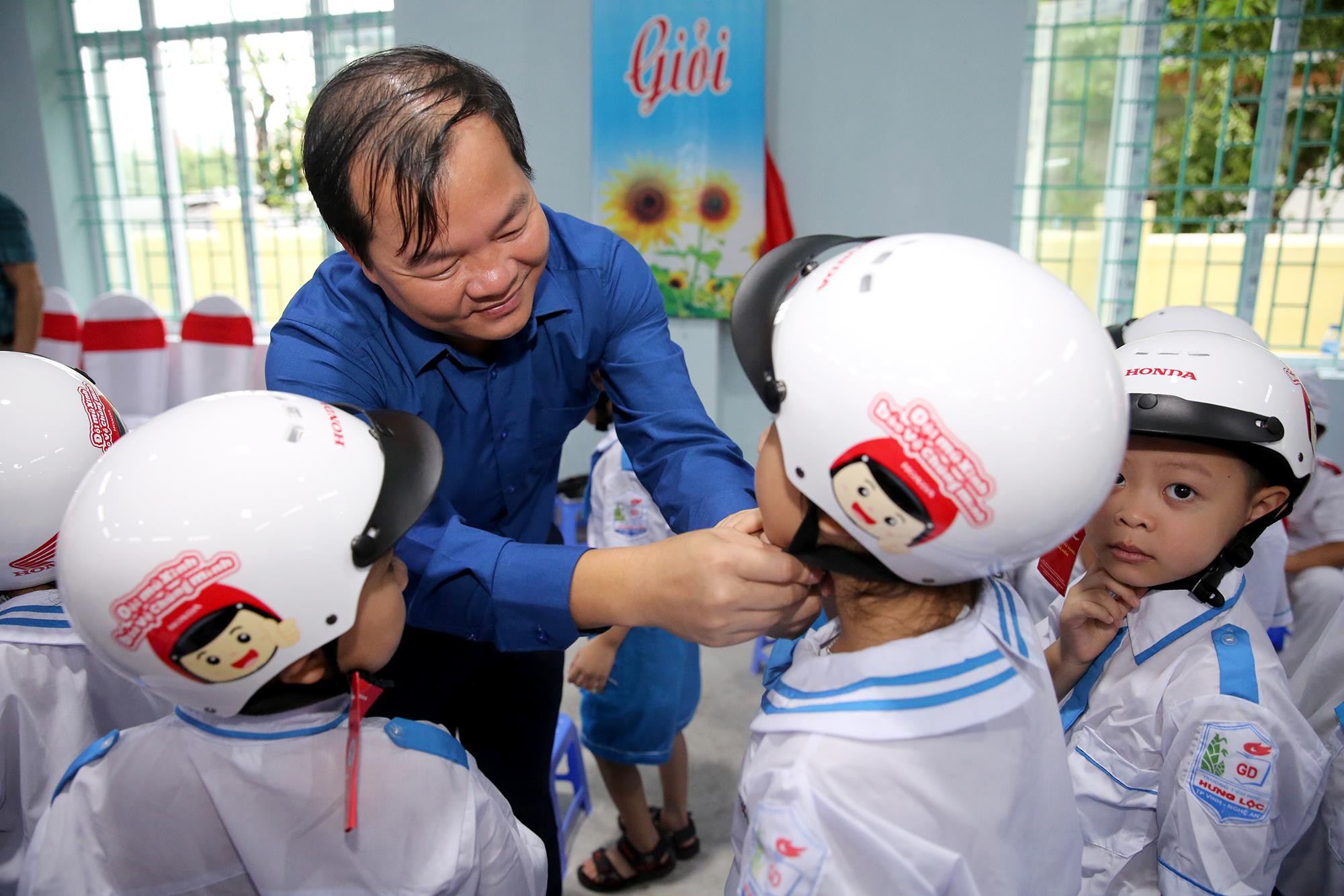Đồng chí Nguyễn Đức An - Phó Giám đốc Sở Giao thông vận tải tặng mũ cho các cháu học sinh lớp 1. Ảnh: Đức Anh