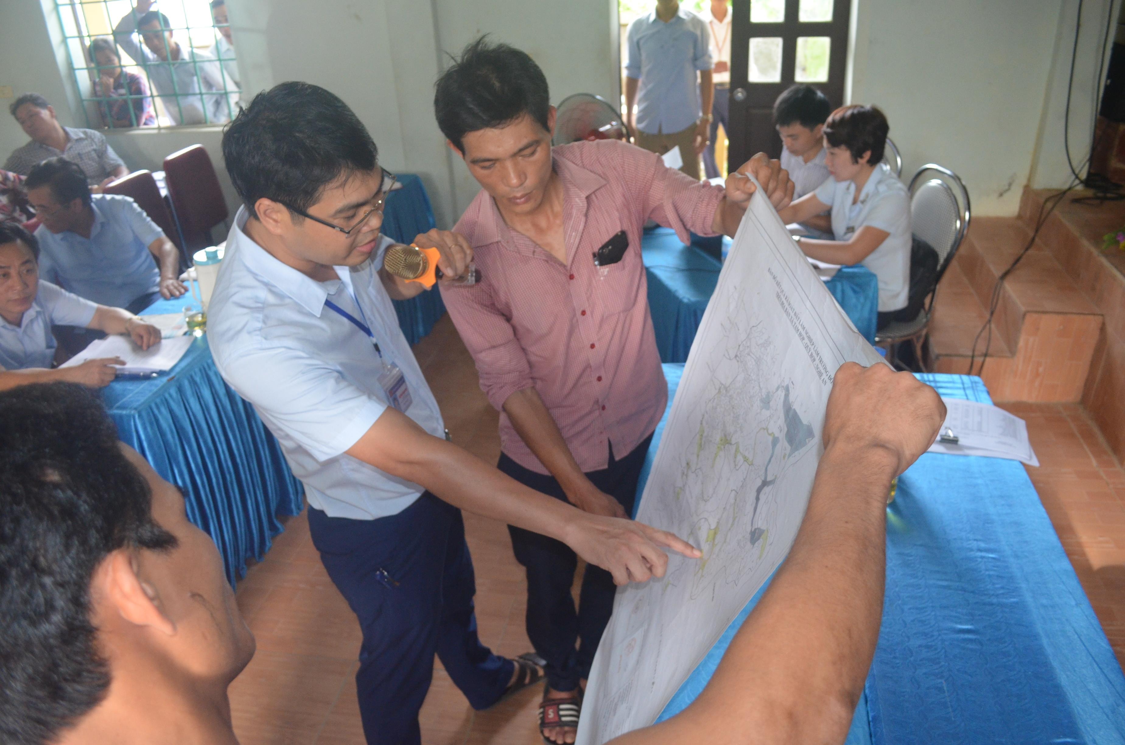 Đại diện phòng TN&MT chỉ dẫn ranh giới các diện tích đất tại bản đồ kèm theo quyết định 203 cho người dân xomsLong Thành. Ảnh: Nhật Lân 