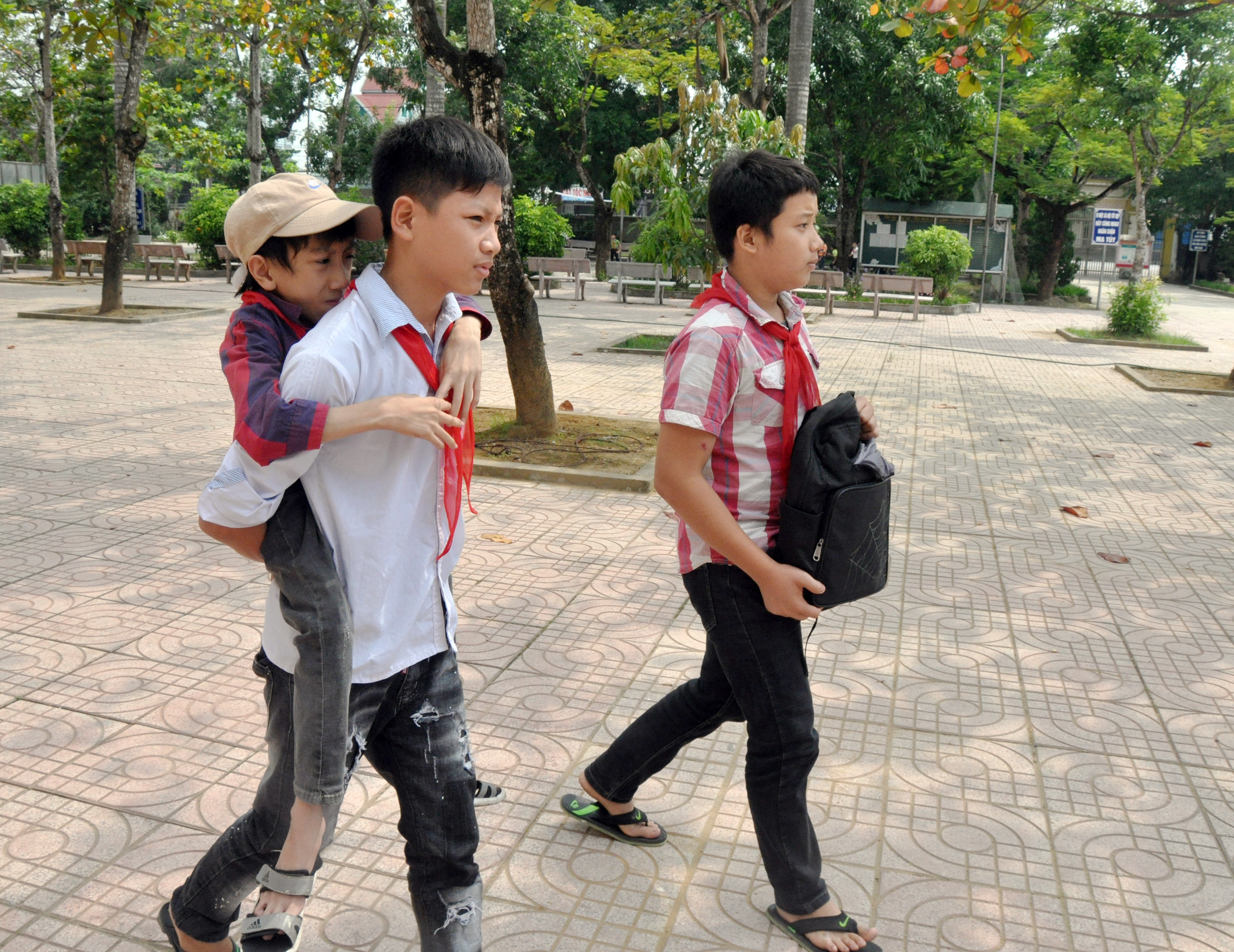 Nguyễn Mạnh Chiến được hai bạn cùng lớp là Phan Ngọc Tâm Đoan và Nguyễn Văn Trịnh thay nhau cõng vào lớp. Ảnh tư liệu