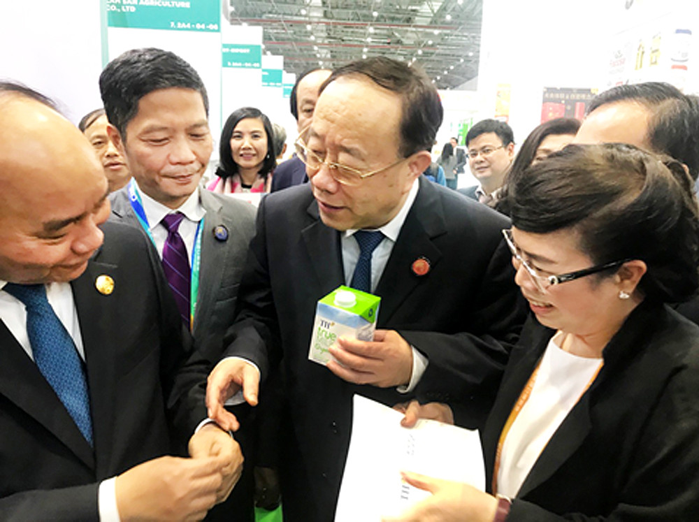 Thủ tướng Nguyễn Xuân Phúc và Thứ trưởng Bộ Thương mại Trung Quốc Vương Bính Nam tìm hiểu về sản phẩm sữa tươi hữu cơ TH true MILK Organic tại Hội chợ Nhập khẩu Quốc tế Trung Quốc 2018 (CIIE 10/2018) tại Thượng Hải.