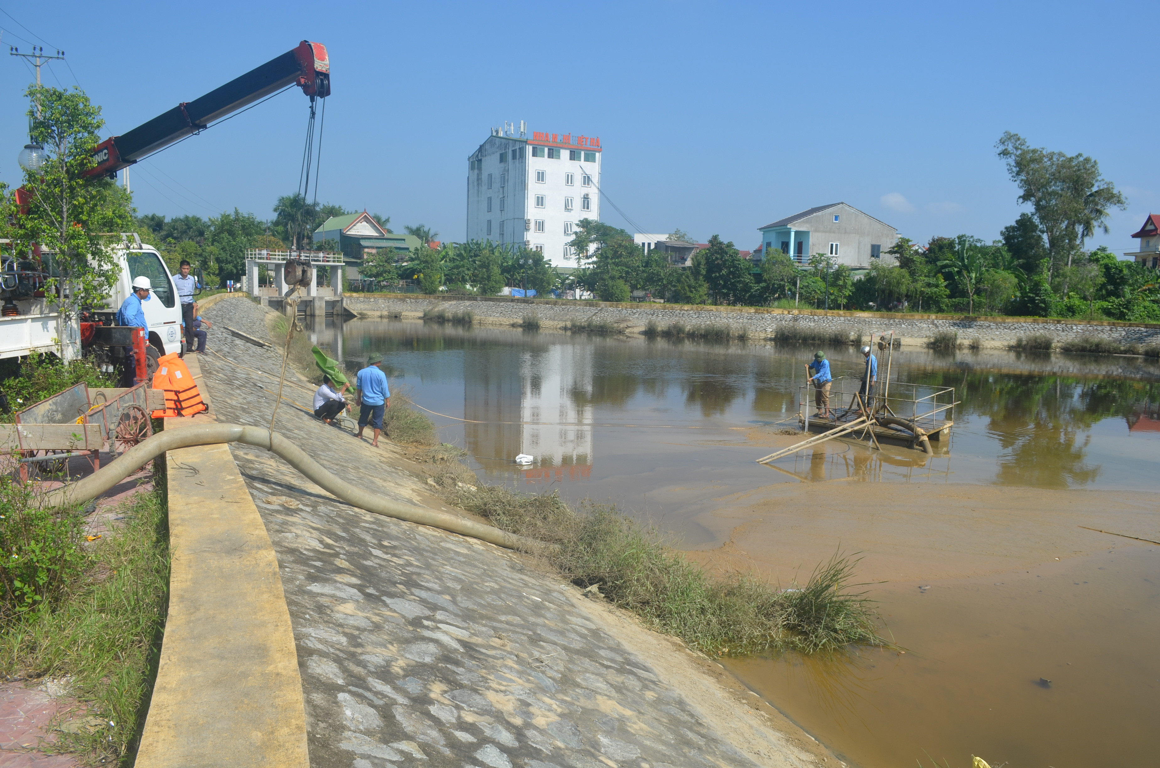 Hàng chục cán bộ, công nhân Công ty CP Cấp nước Nghệ An vận hành thiết bị, hút bùn thải ra khỏi hồ điều hòa. ẢNh: Nhật Lân