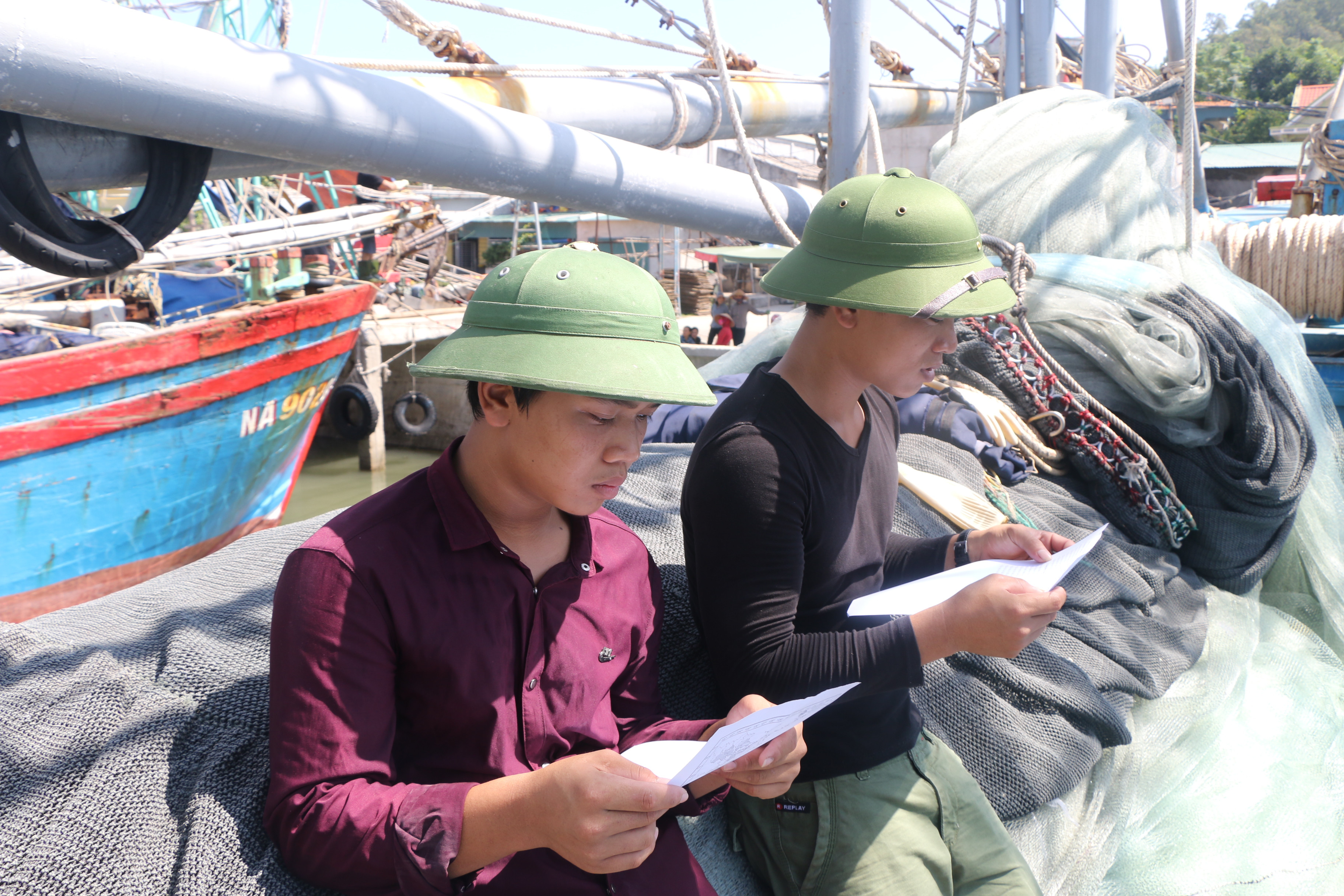 Ngư dân Quỳnh Lập đọc tờ rơi tuyên truyền pháp luật ngay trên thuyền. Ảnh: G.H