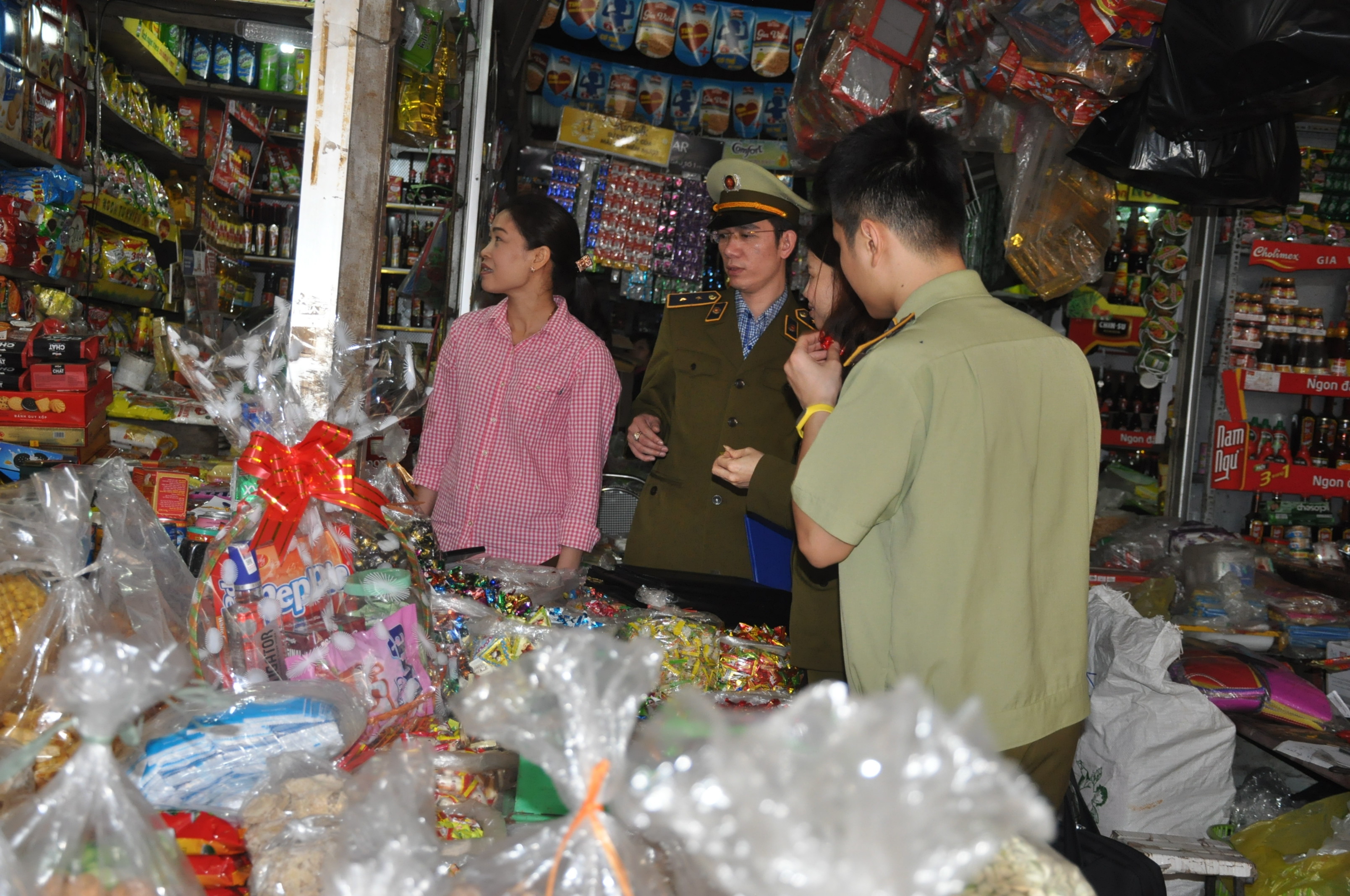 Lực lượng QLTT kiểm tra hàng bánh kẹo ở Chợ Vinh. Ảnh: Thu Huyền