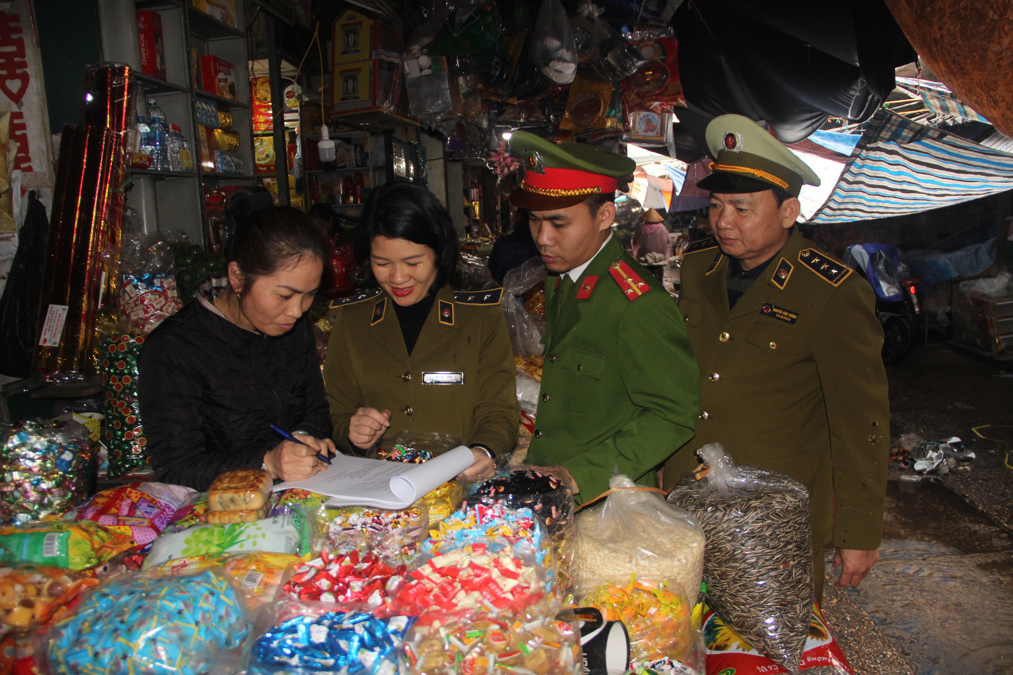 Cơ quan chức năng kiểm tra bánh kẹo tết tại chợ Vinh. Ảnh Quang An