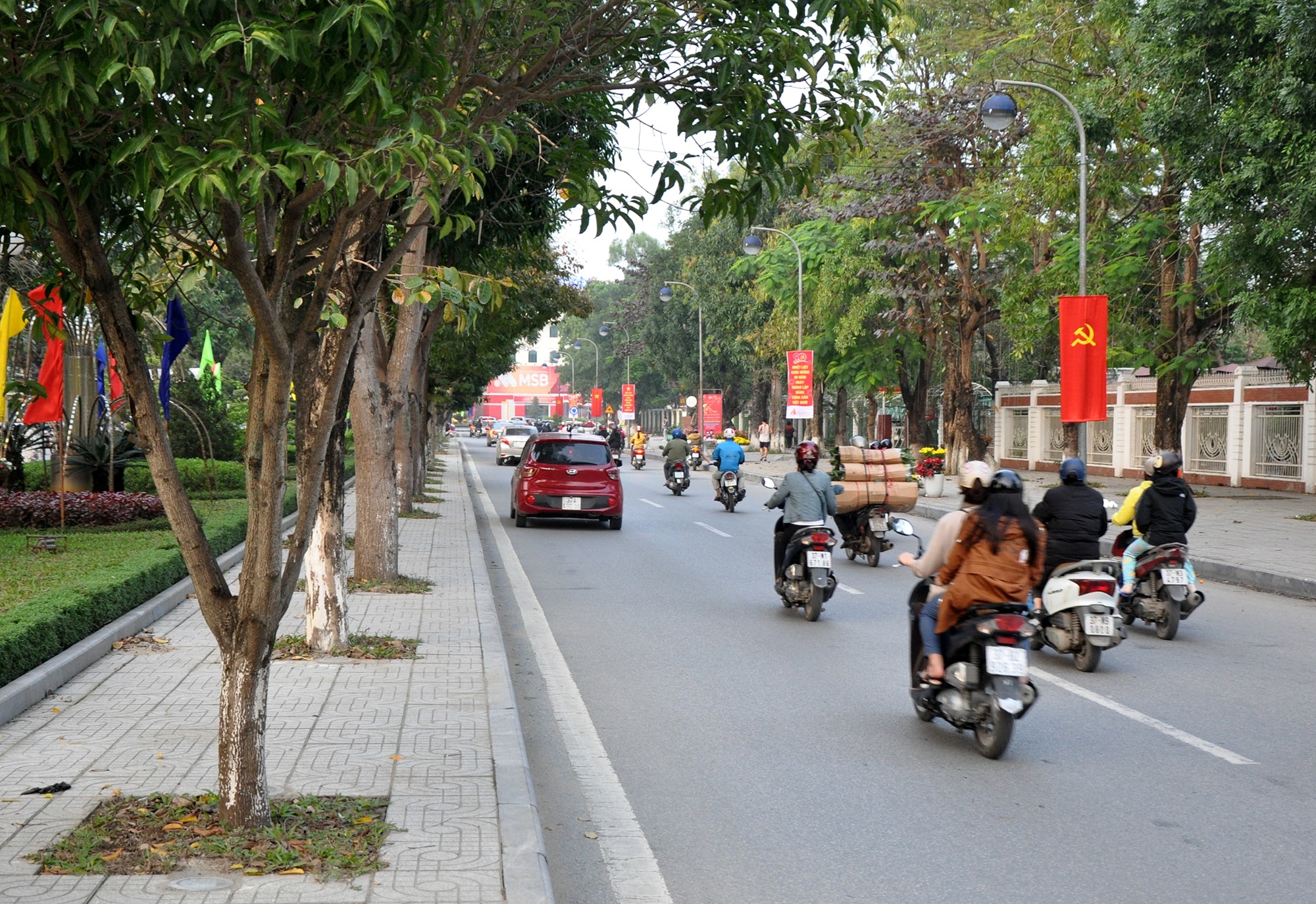 Ở thành phố Vinh, tuyến đường chính được trang hoàng lộng lẫy bằng màu cờ Tổ quốc và vô số băng rôn, khẩu hiệu khiến cho không khí đón năm mới thêm rộn ràng. Trong ảnh: Đường Lê Mao - một trong những tuyến đường đẹp nhất thành phố. Ảnh: Công Kiên