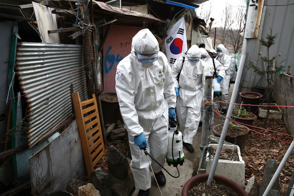 Quân nhân Hàn Quốc mặc đồ bảo hộ phun khử trùng tại làng Guryong, Seoul hôm 3/3. Ảnh: Getty