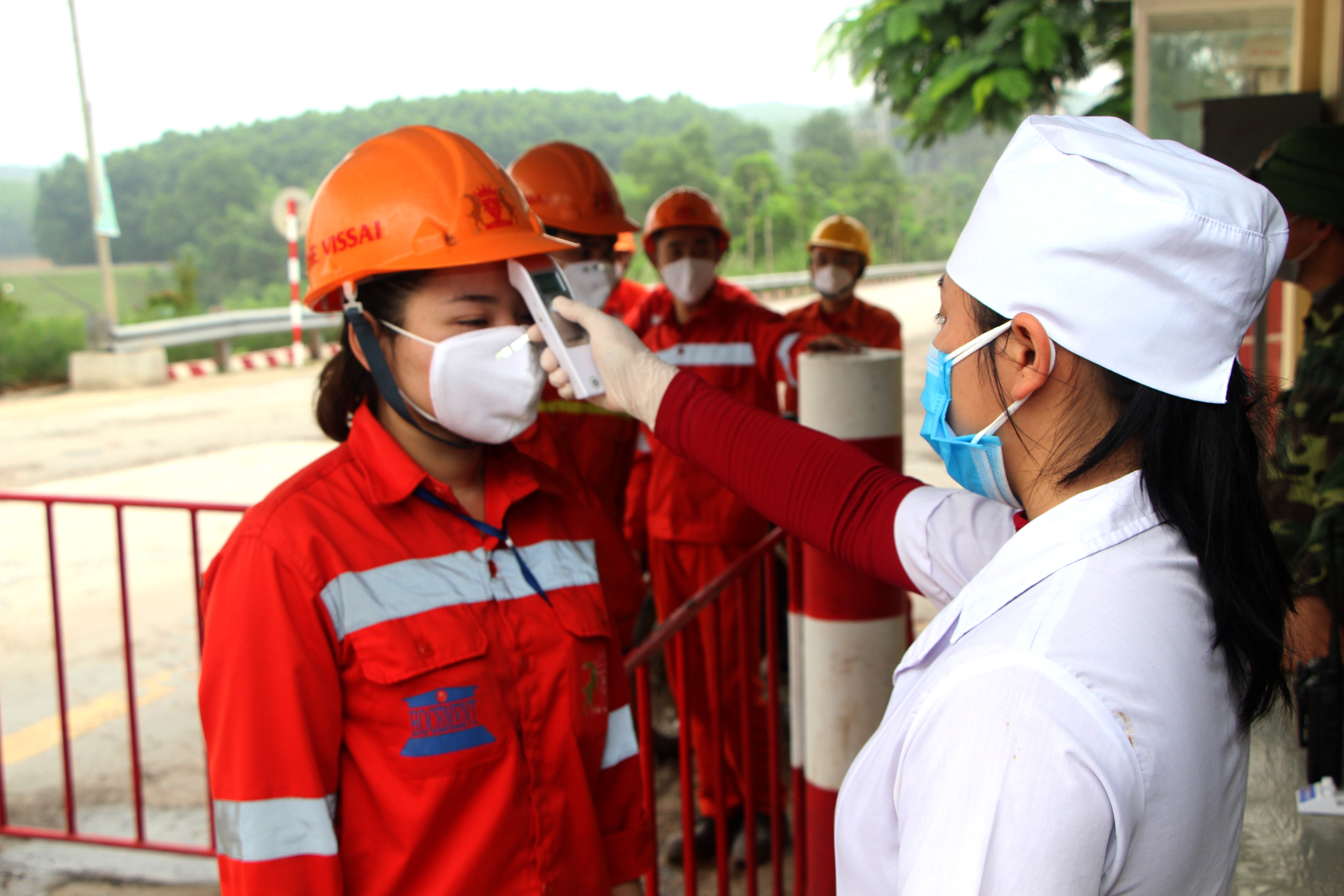 Đo thân nhiệt cho công nhân thay ca ở Nhà máy xi măng Đo Lương. Ảnh: Nguyên Nguyên