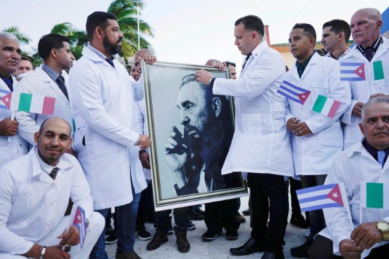 Các bác sỹ Cuba cùng chân dung Chủ tịch FIdel Castro trong lễ tiễn trước khi lên đường giúp Italy chống Covid-19. Ảnh: Reuters